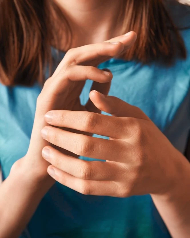 Close-up of two hands, one of a woman and the other of a child, gently touching each other.