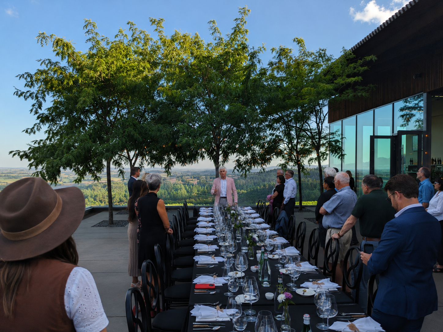 Winery guests gathered around a vineyard dinner table listening to a winemaker presentation.
