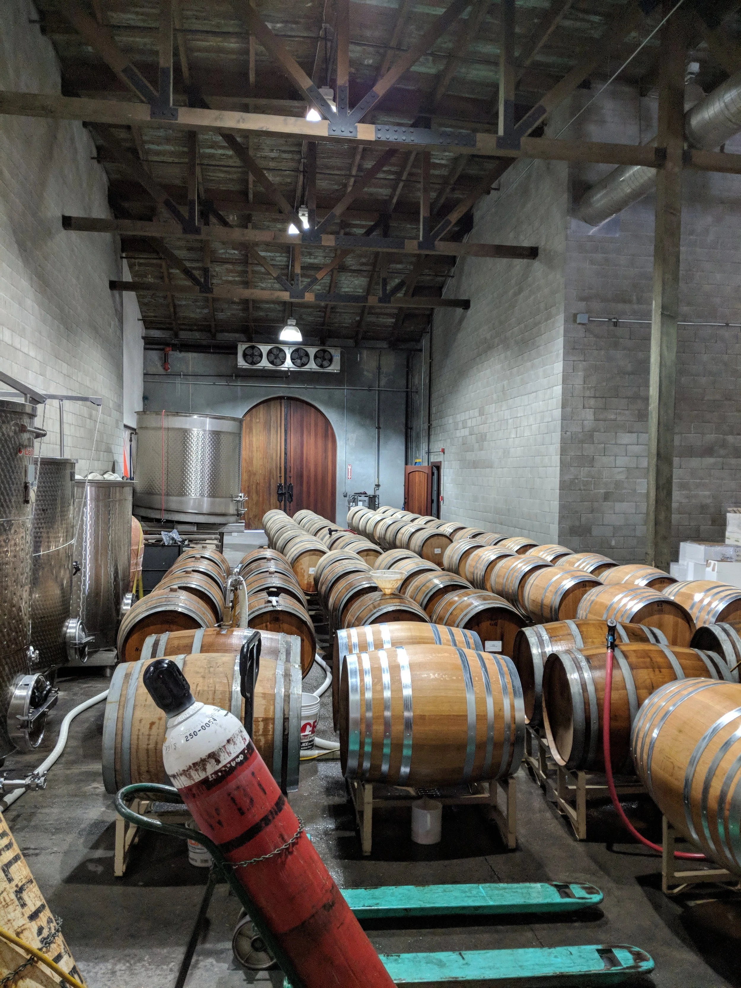 Working winery cellar with wine barrels, tanks, and production equipment used in day-to-day winery operations.