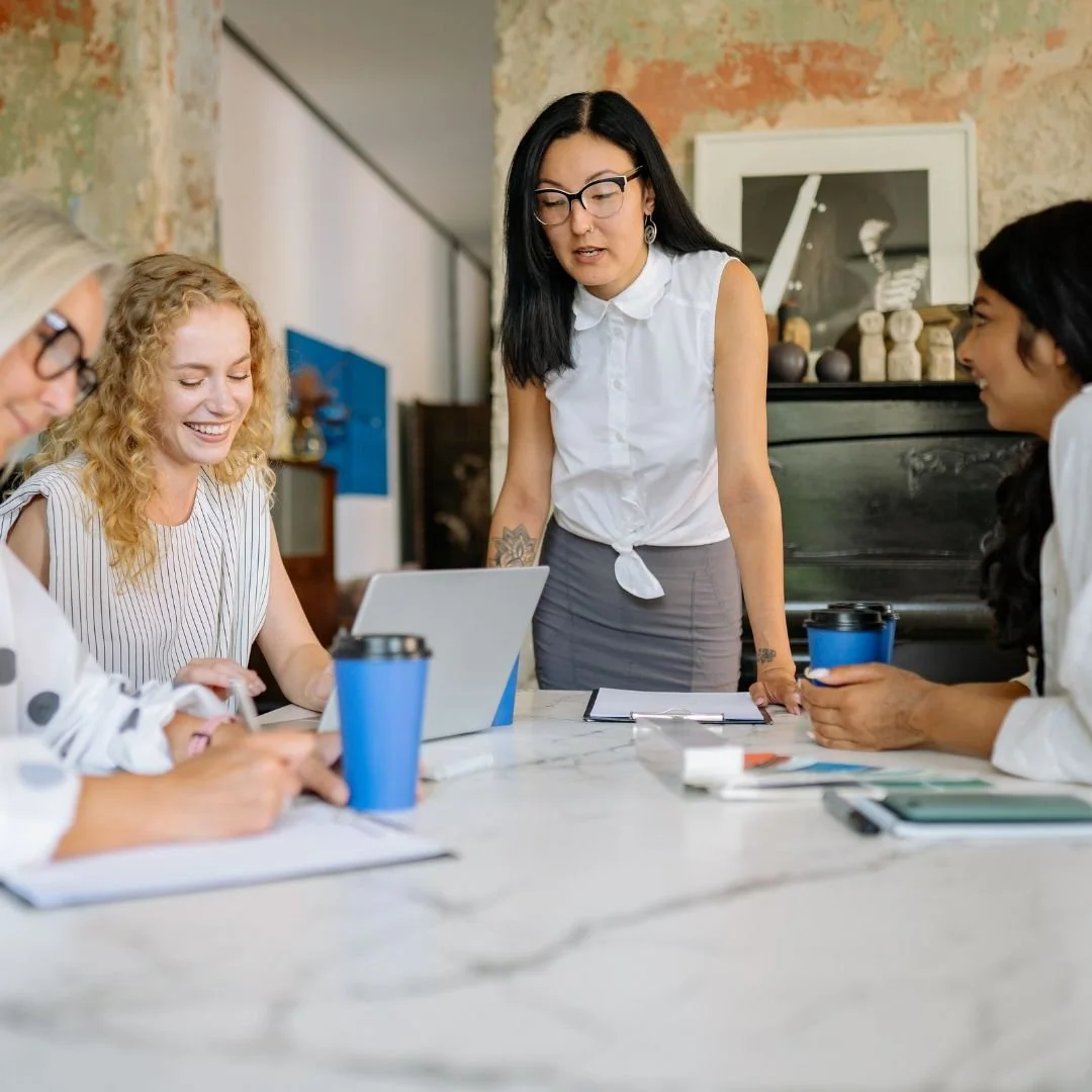 An executive leader facilitating a dynamic team discussion with laptops and notebooks, showcasing high-level collaboration and authoritative presence.