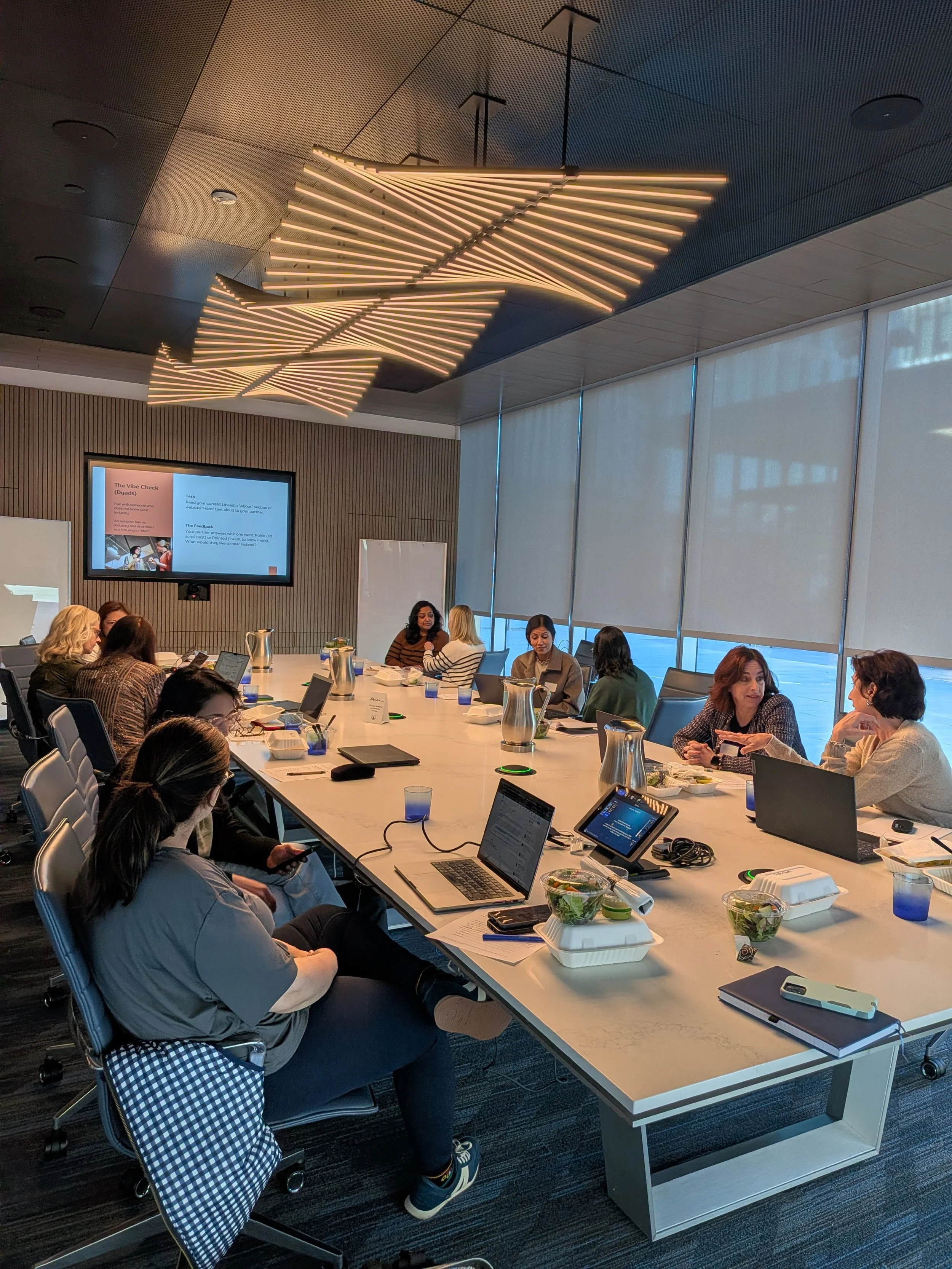 Professional women at an Elevate workshop in San Carlos auditing their LinkedIn profiles to remove corporate jargon and overused buzzwords.