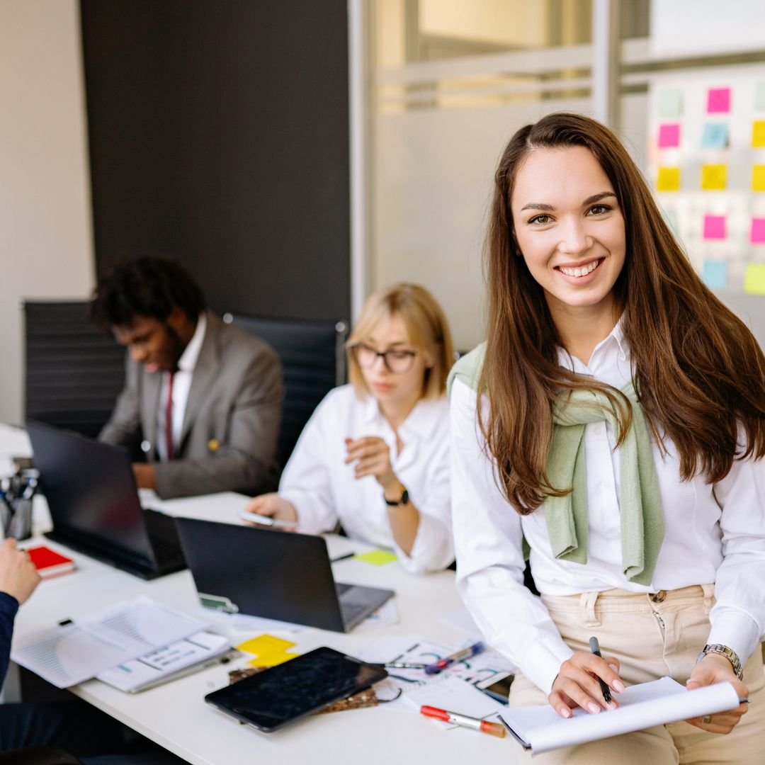 A professional woman working on a laptop in a modern, collaborative office space, representing the shift toward AI-integrated workflows for mid-level professionals.