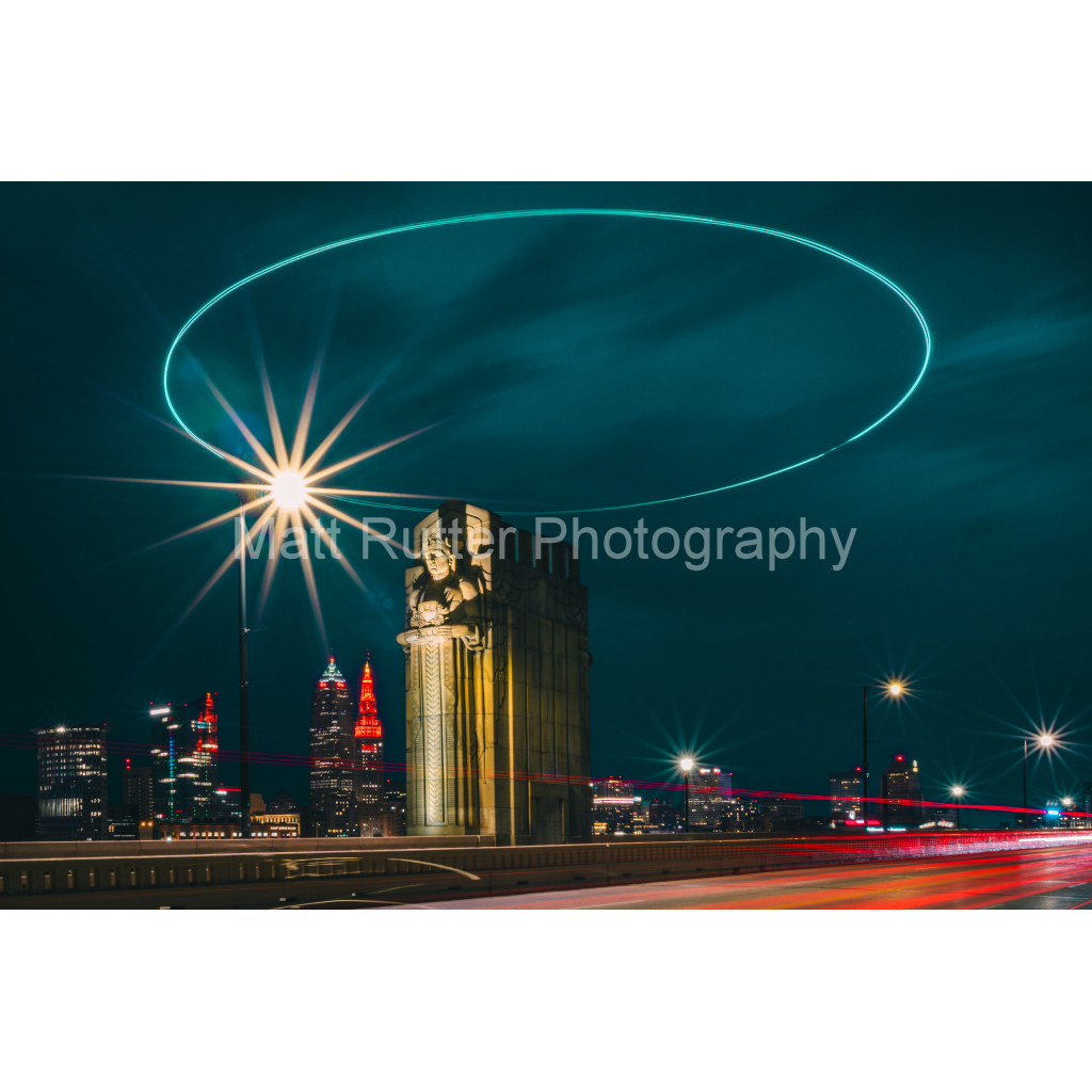 Cleveland's Guardians of Traffic statue glowing at night with a light halo on the Hope Memorial Bridge.