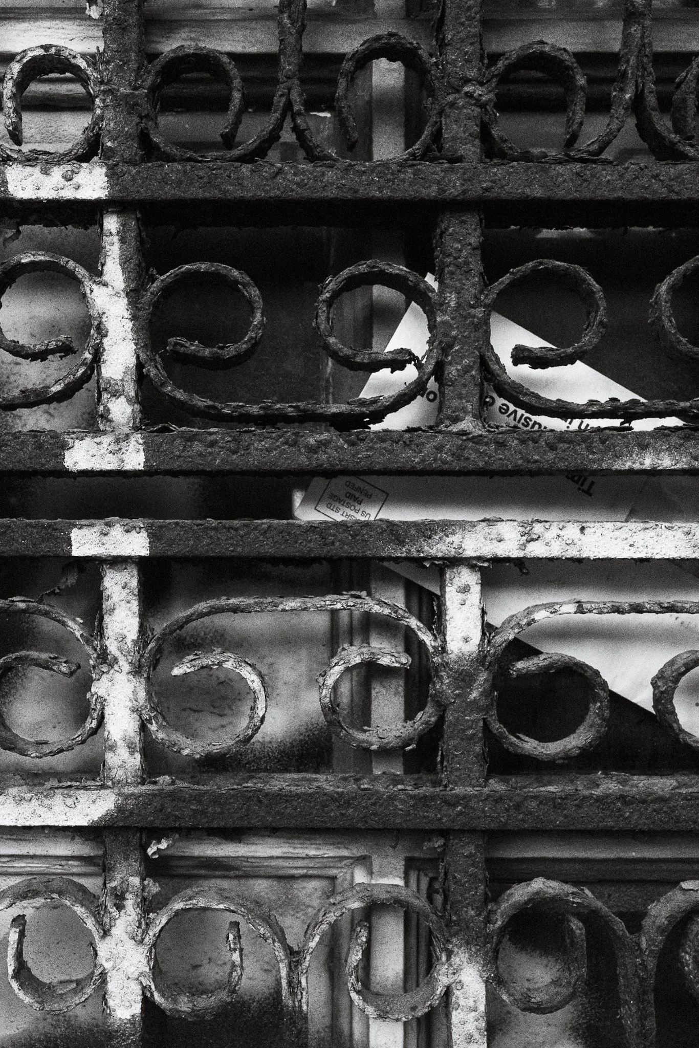 Close-up of an old, rusty, decorative iron fence with circular and heart-shaped patterns.