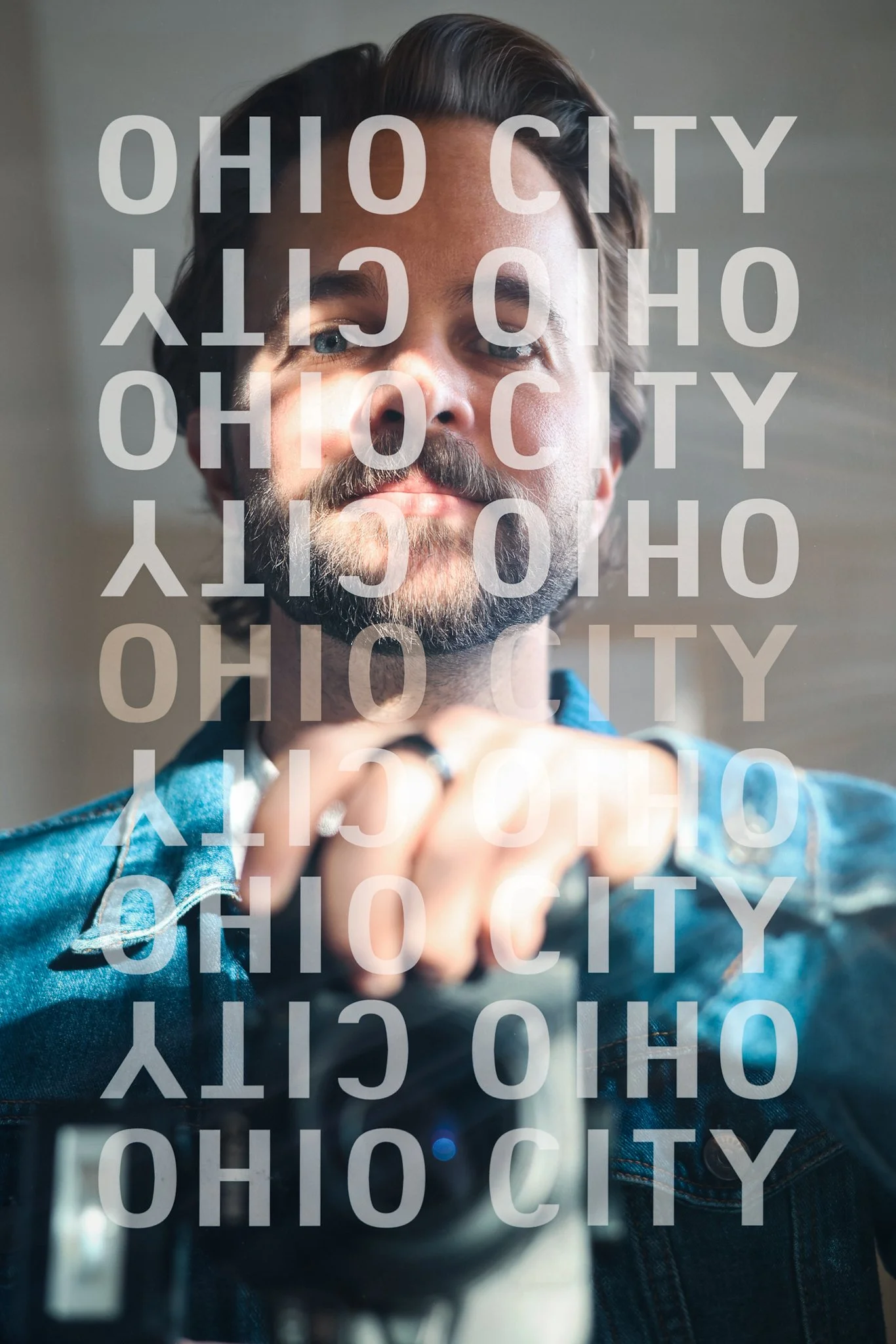 A double exposure portrait of a bearded man with long hair in a denim jacket, gazing thoughtfully under soft light, overlaid with translucent "OHIO CITY" text in varied sizes and angles, enhanced by subtle color grading for a moody urban vibe