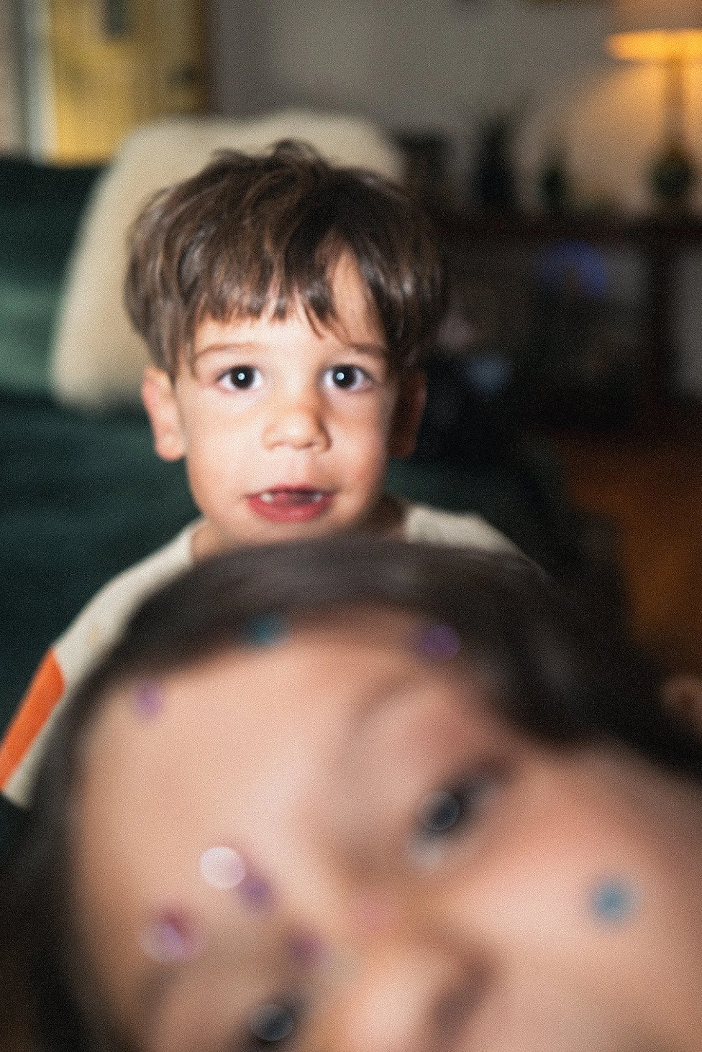 A young boy with dark brown hair and fair skin looking toward the camera inside a vehicle, with out-of-focus background.