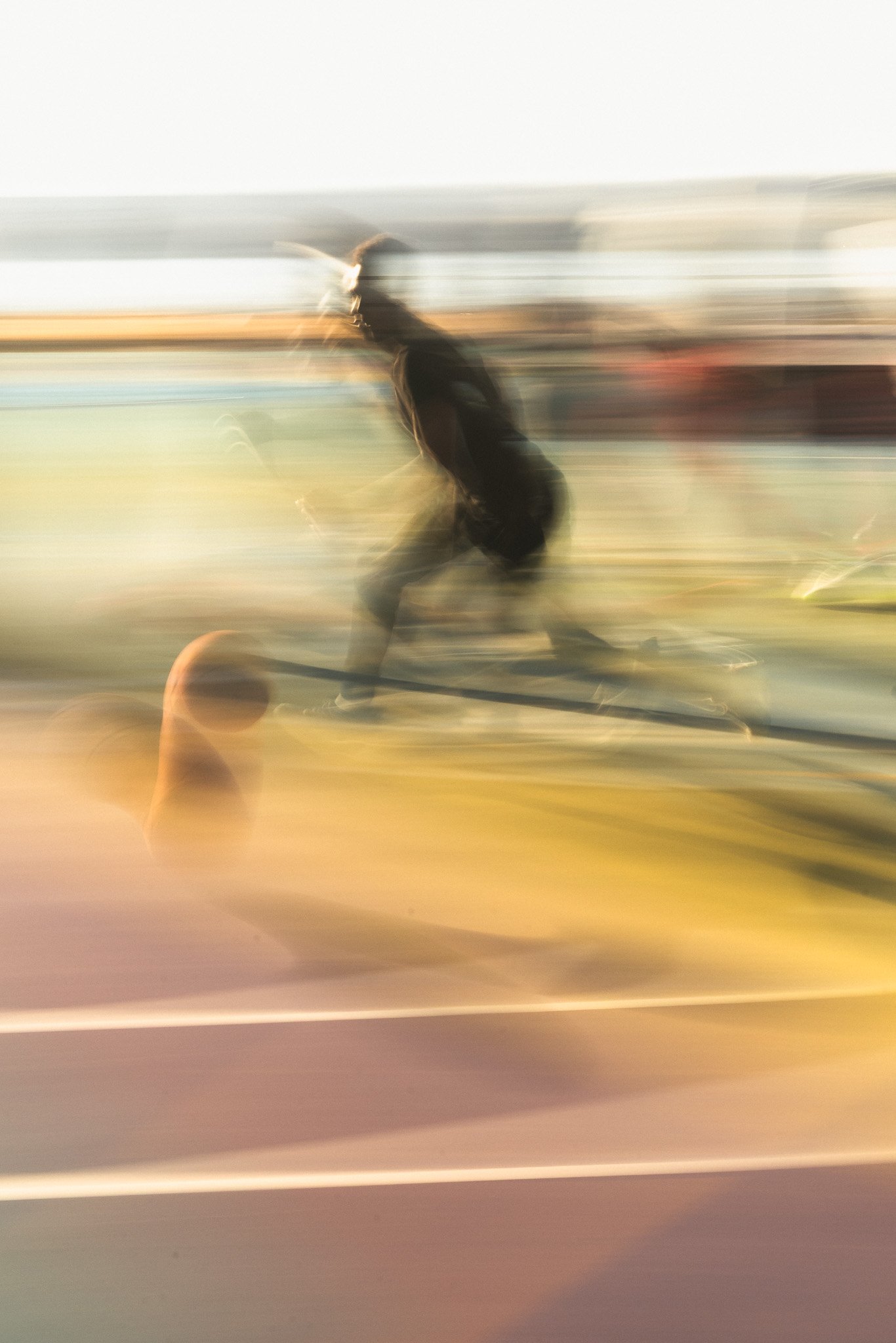 A long-exposure photograph captures a basketball player dribbling and sprinting on an indoor court, rendered with intentional motion blur that elongates their body into dynamic streaks of black clothing and white sneakers against glowing yellow lines