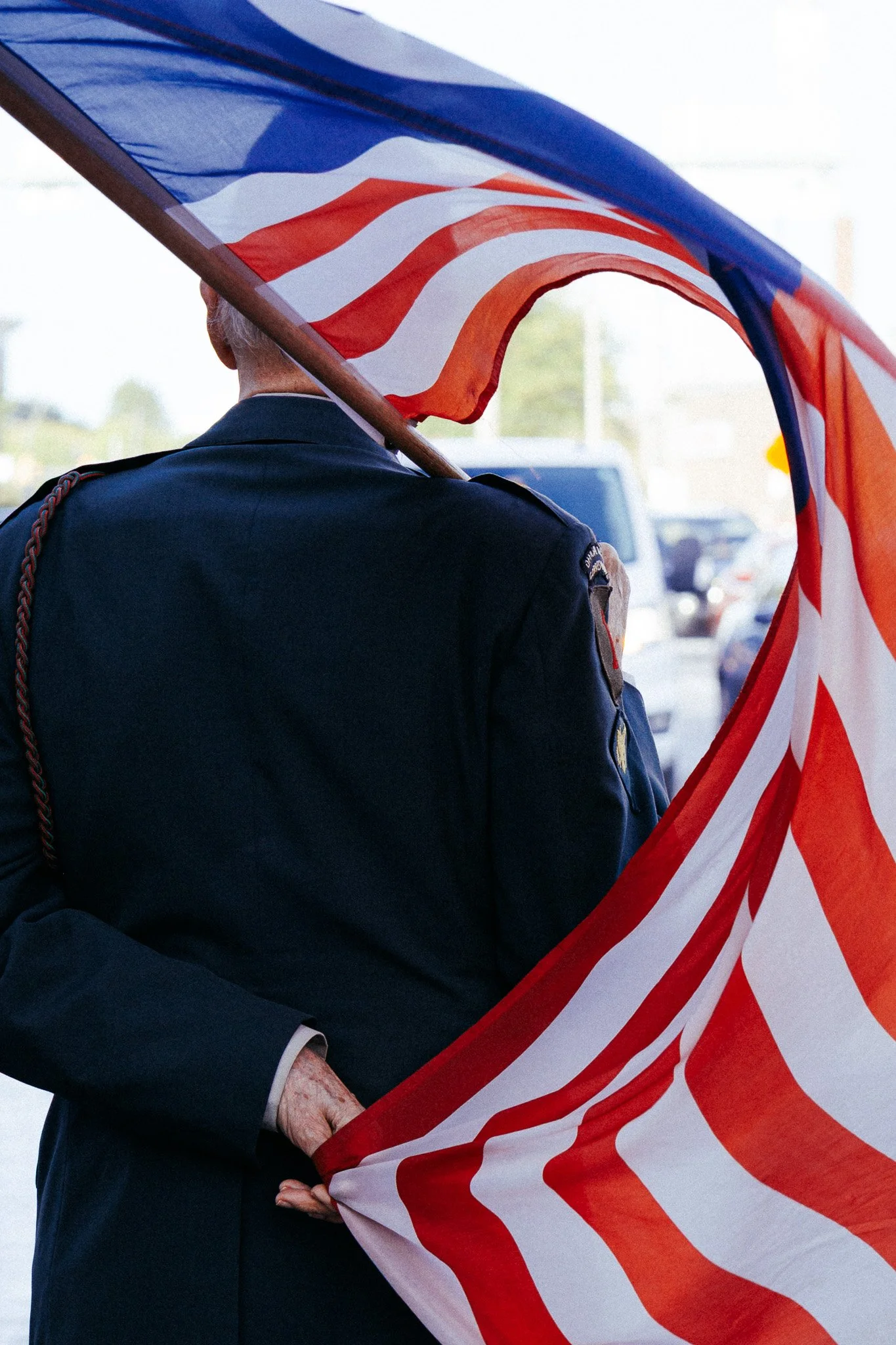 A man in a dark uniform holding an American flag at an outdoor event.