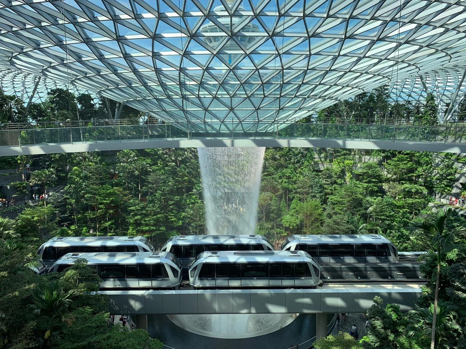 Changi intra terminal trains in front of a large indoor waterfall