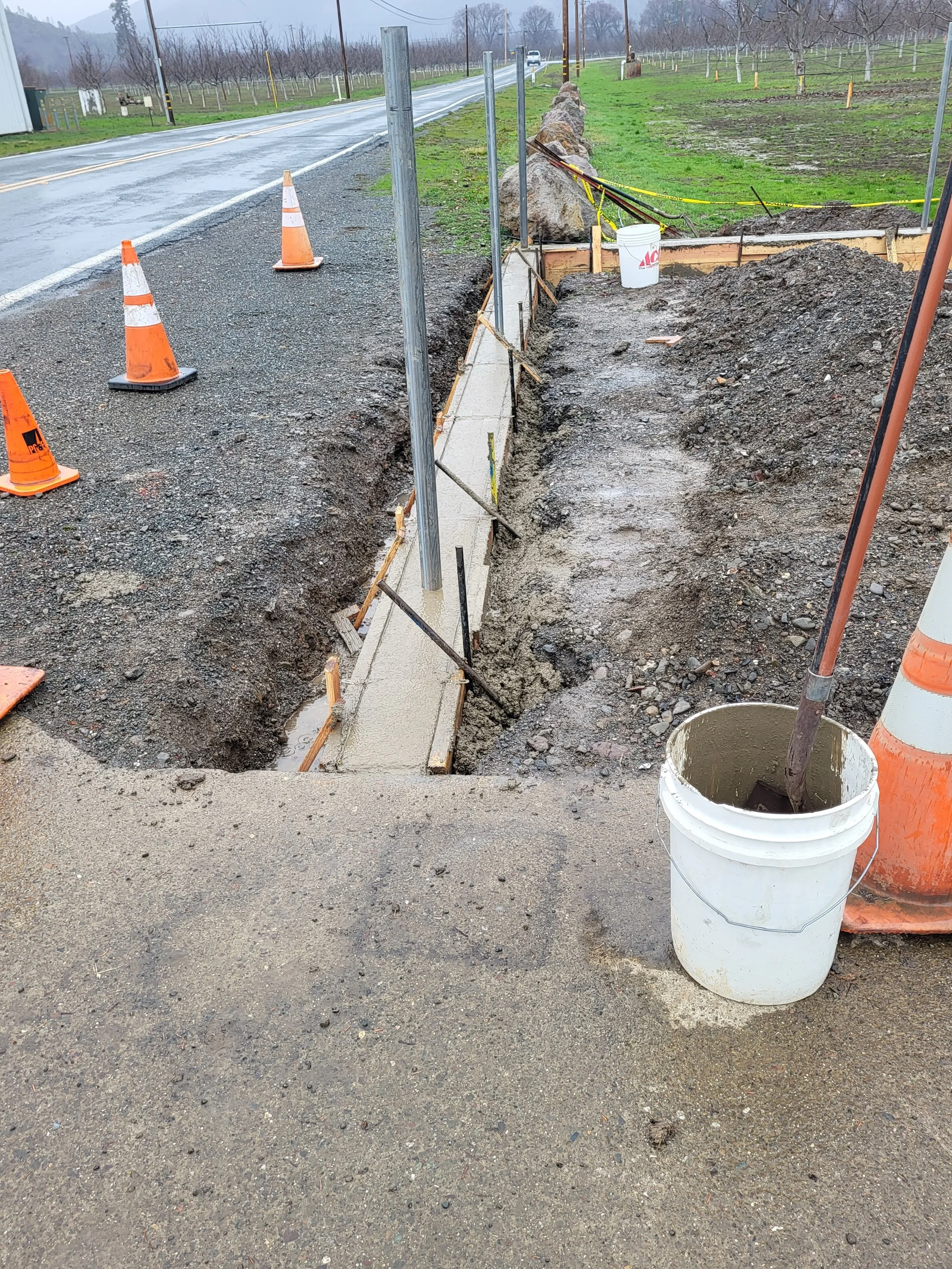Finished flat work of newly poured concrete in form boards for foundation stem wall for installation of chain link fence.