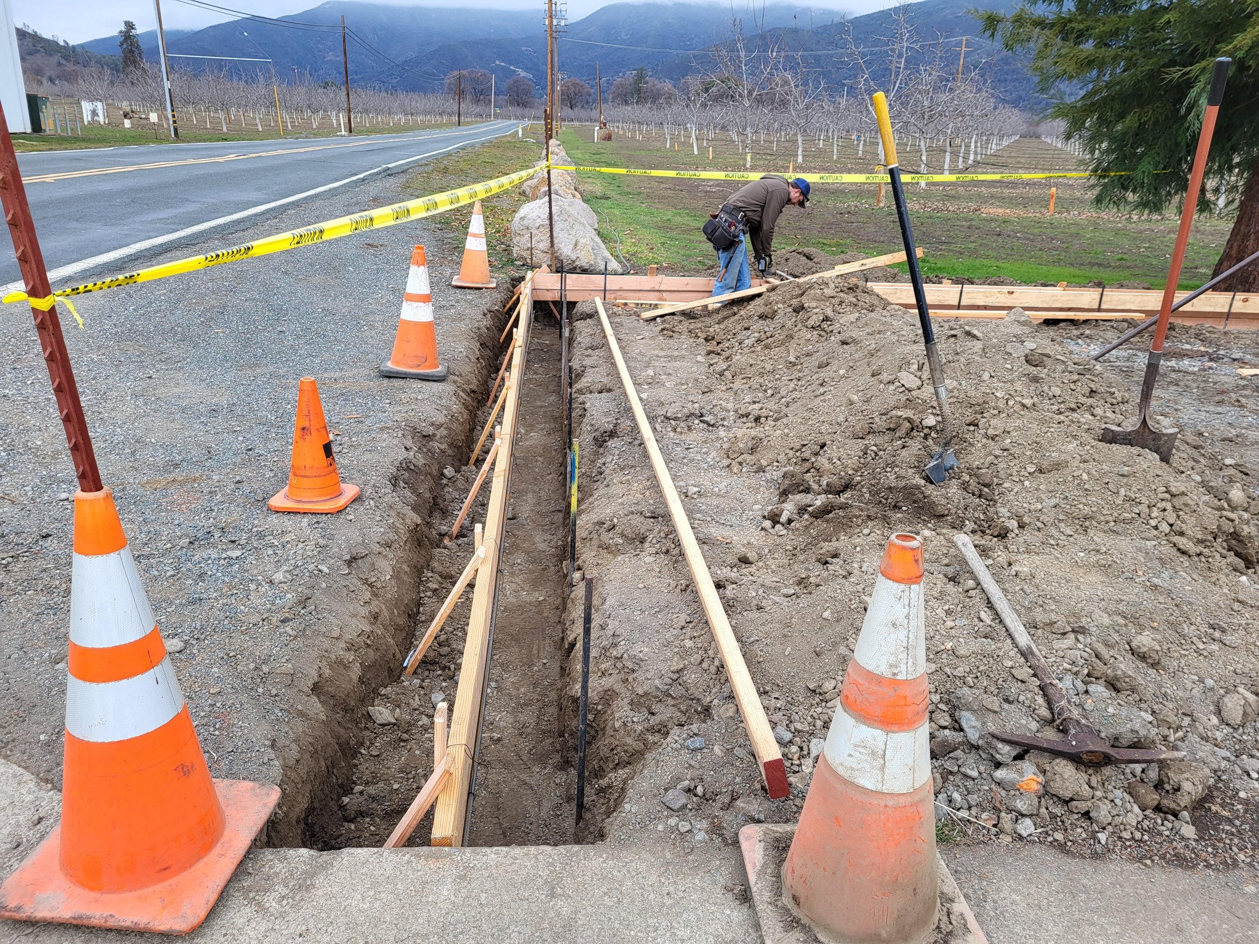 Site work of excavated footing with contractor building forms for concrete.