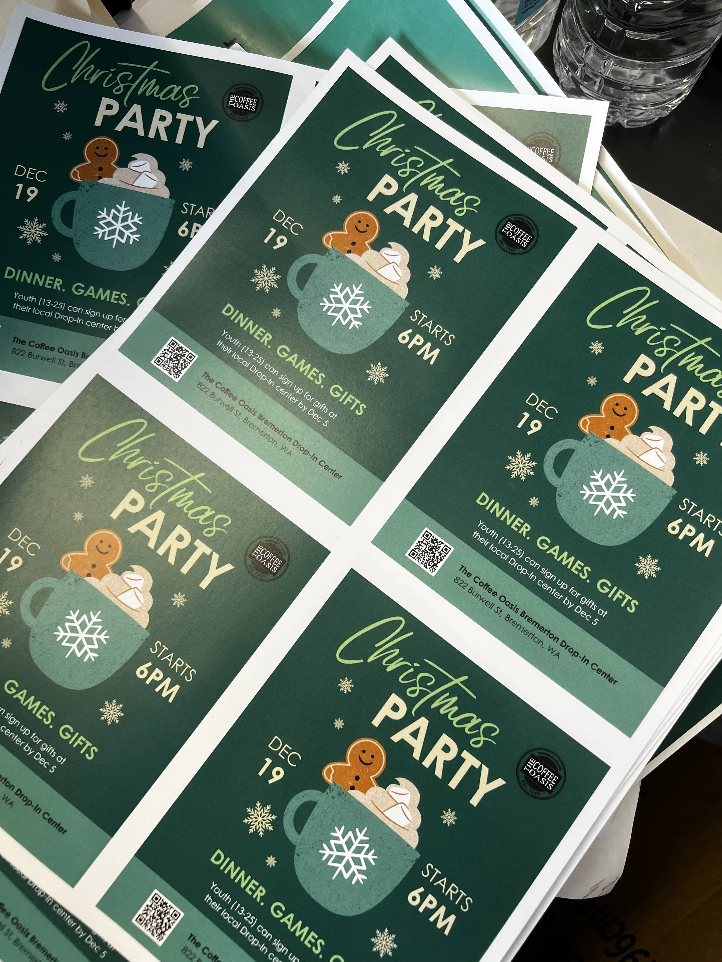 Flyers for a Christmas party at The Coffee Oasis featuring a festive green background, a cartoon mug with whipped cream, a gingerbread man, and white snowflakes, scheduled for December 19 starting at 6 PM.