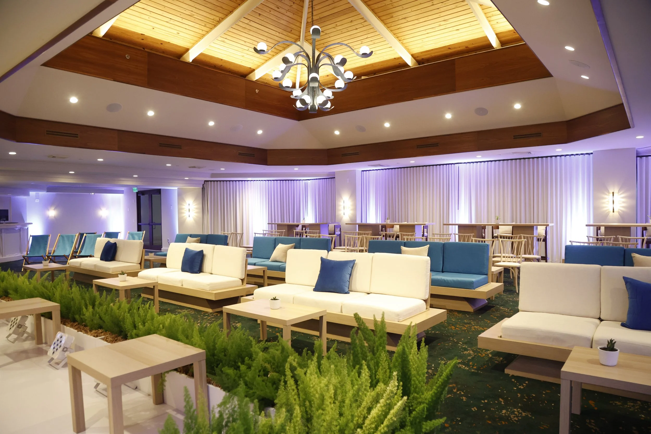 Wide shot of the stage and audience setup at the Arrington Founders Retreat, featuring a clean, modern stage design with natural elements, rows of seating, and attendees gathered in a bright, airy venue.