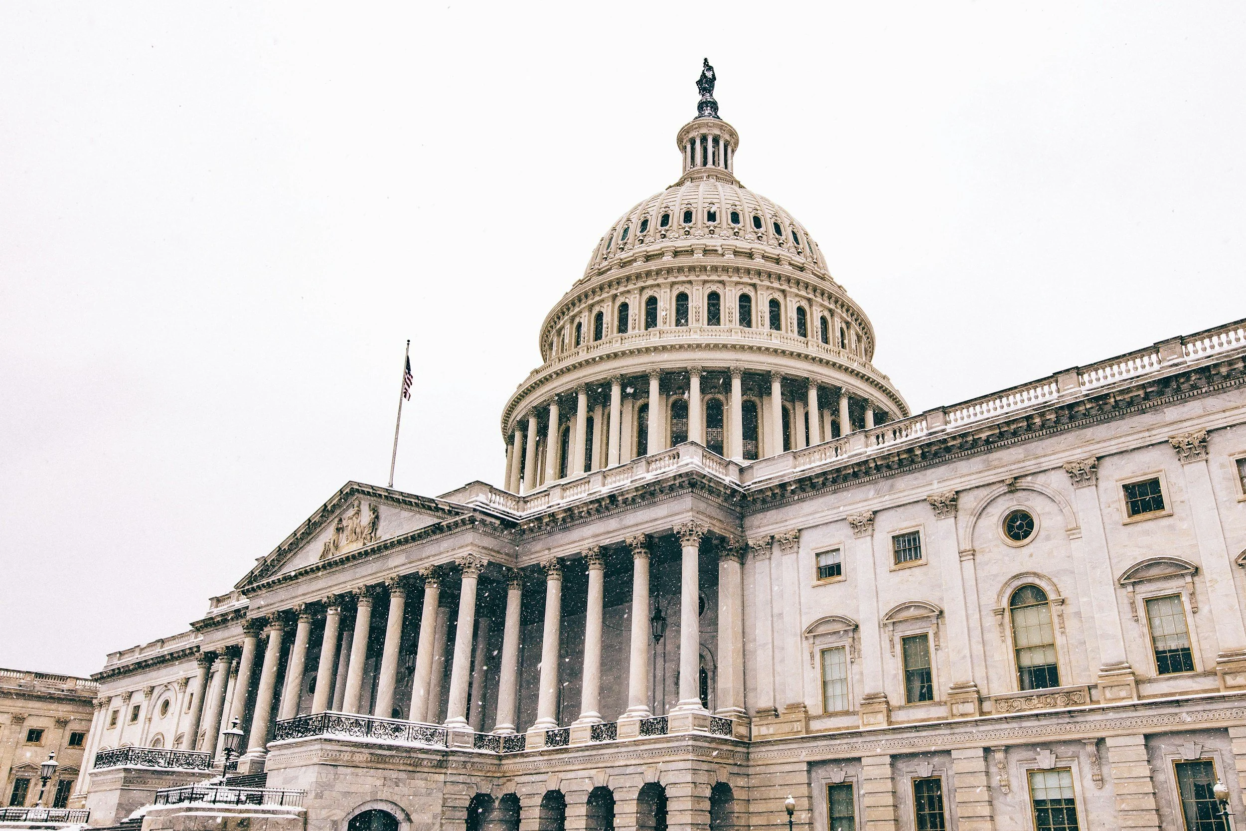 The United States Capitol building with a snow-covered exterior and an overcast sky.