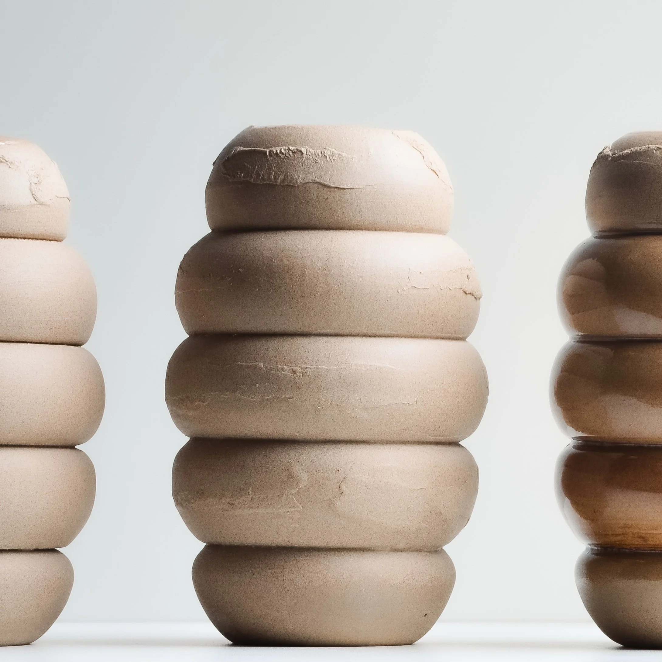 unglazed ceramic tan bud vase on white background