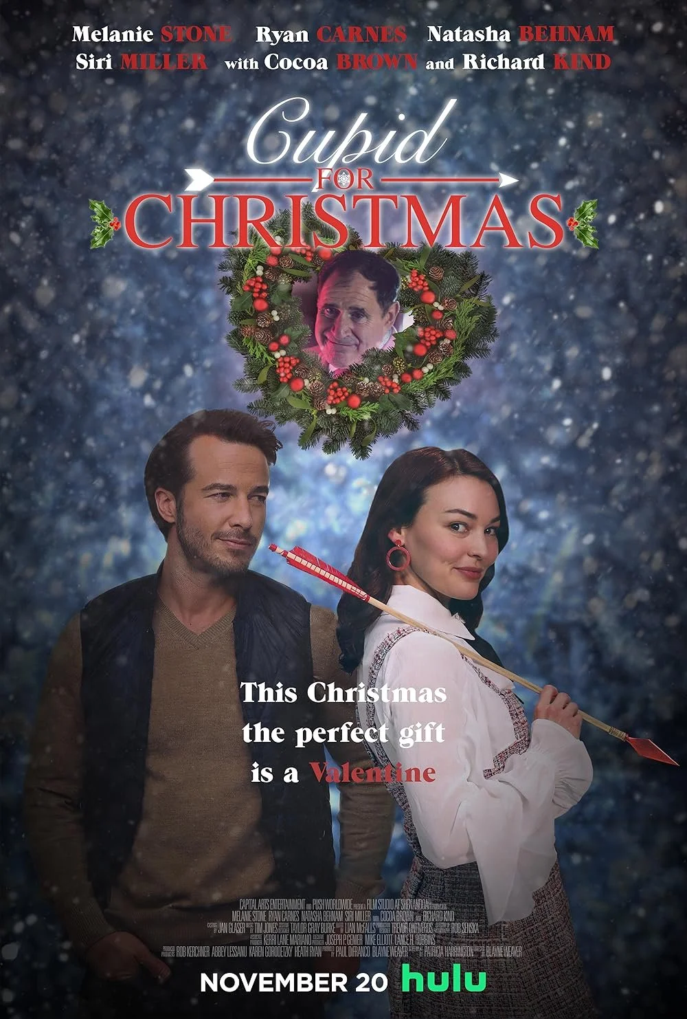 A movie poster for 'Cupid for Christmas' featuring two main characters, Melanie Stone and Ryan Carnes, with a festive background and a Christmas wreath with a man's face inside it. The poster includes text about the movie's release date on Hulu and a holiday message.