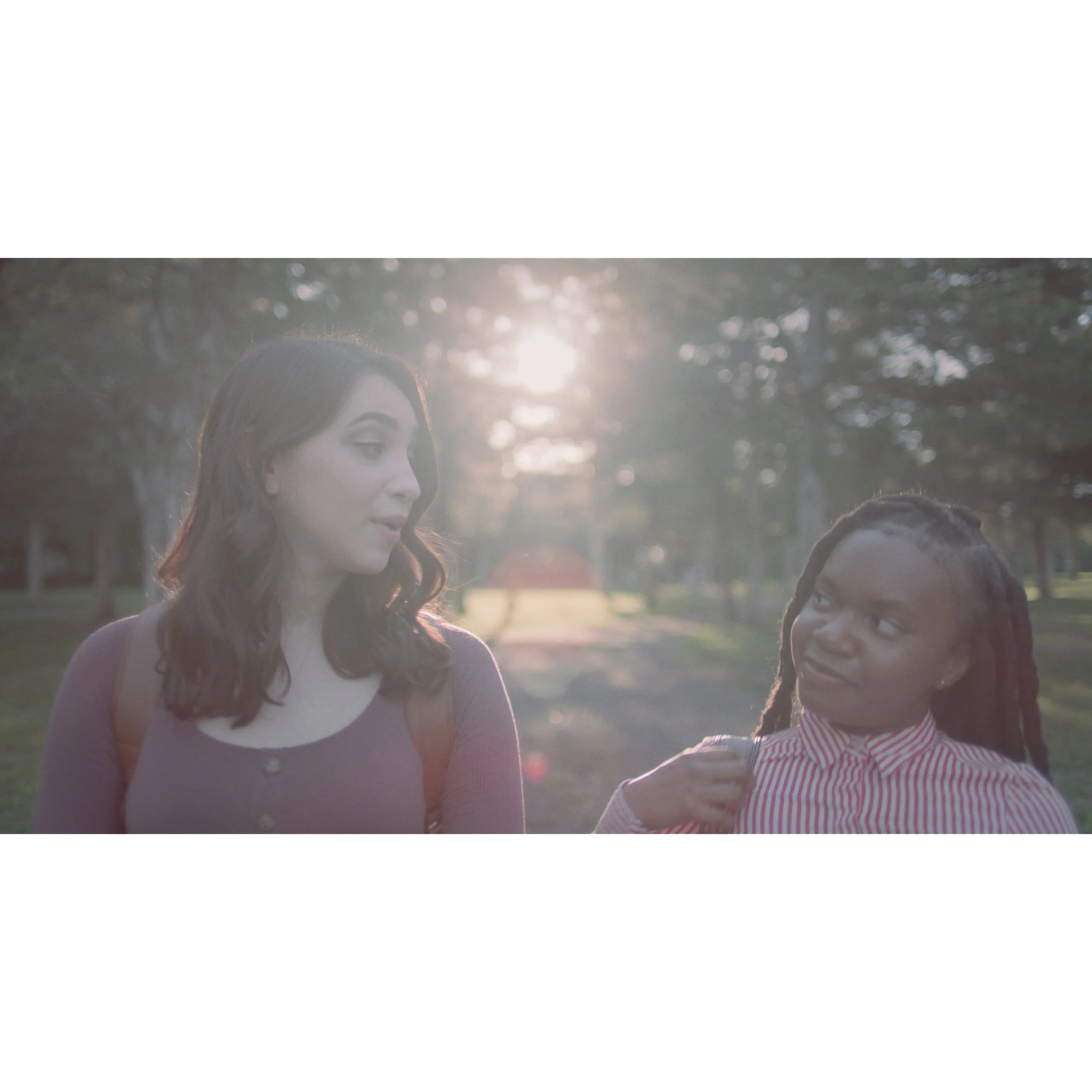Two women talking outdoors during sunset in a park.