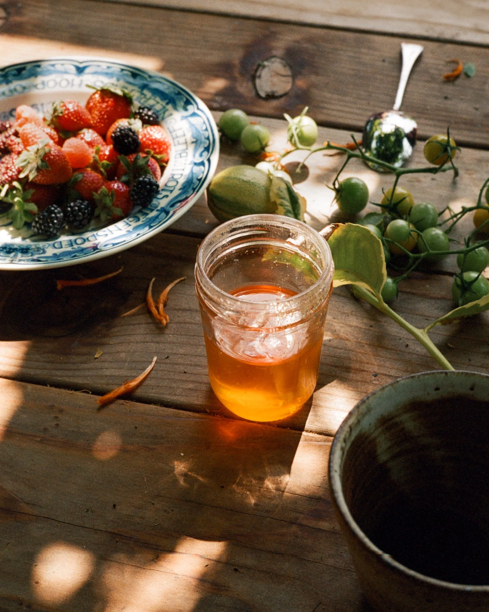 Still life of wooden table with a bowl of mixed berries and a jar of honey