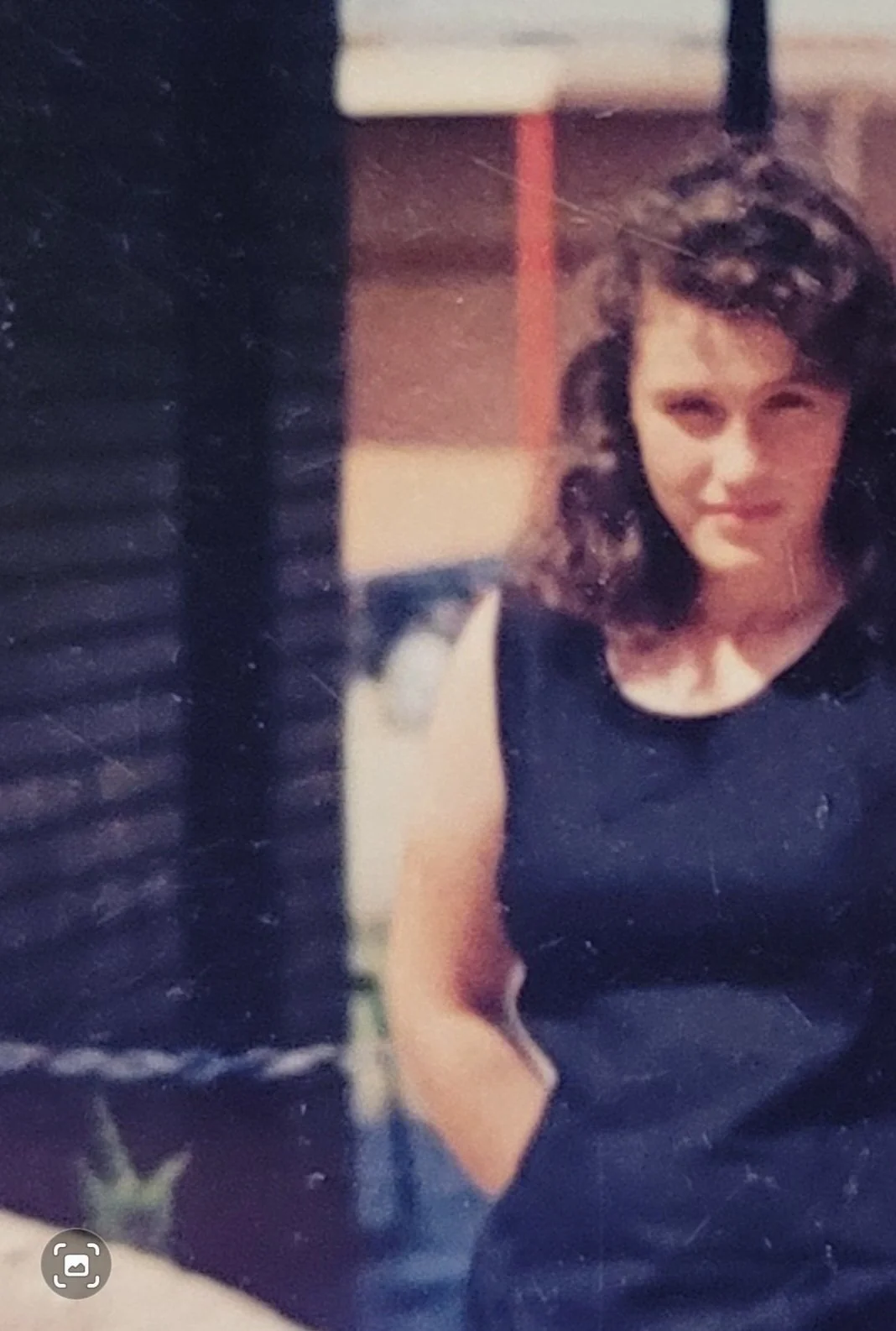 A woman with dark, curly hair wearing a black dress.