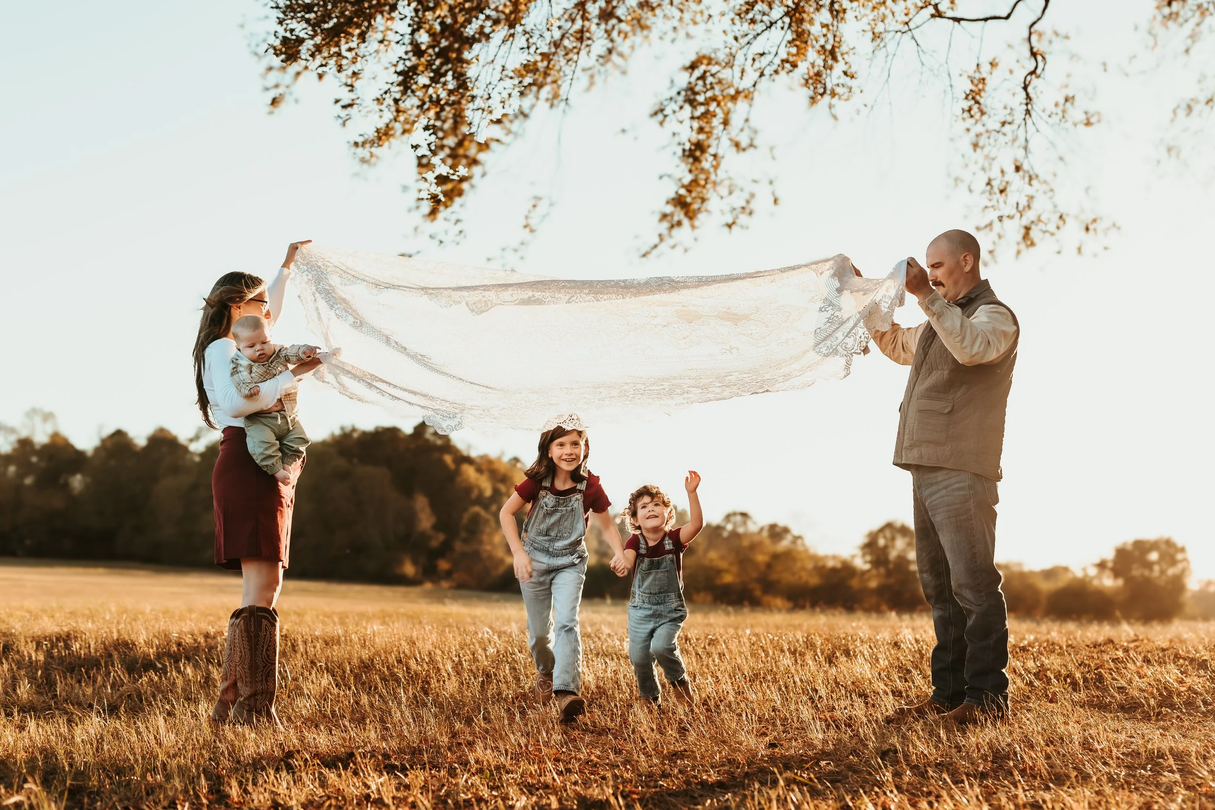 Lifestyle family photo of parents and children running and exploring a sunlit field together, captured during a natural outdoor family session in Georgia.