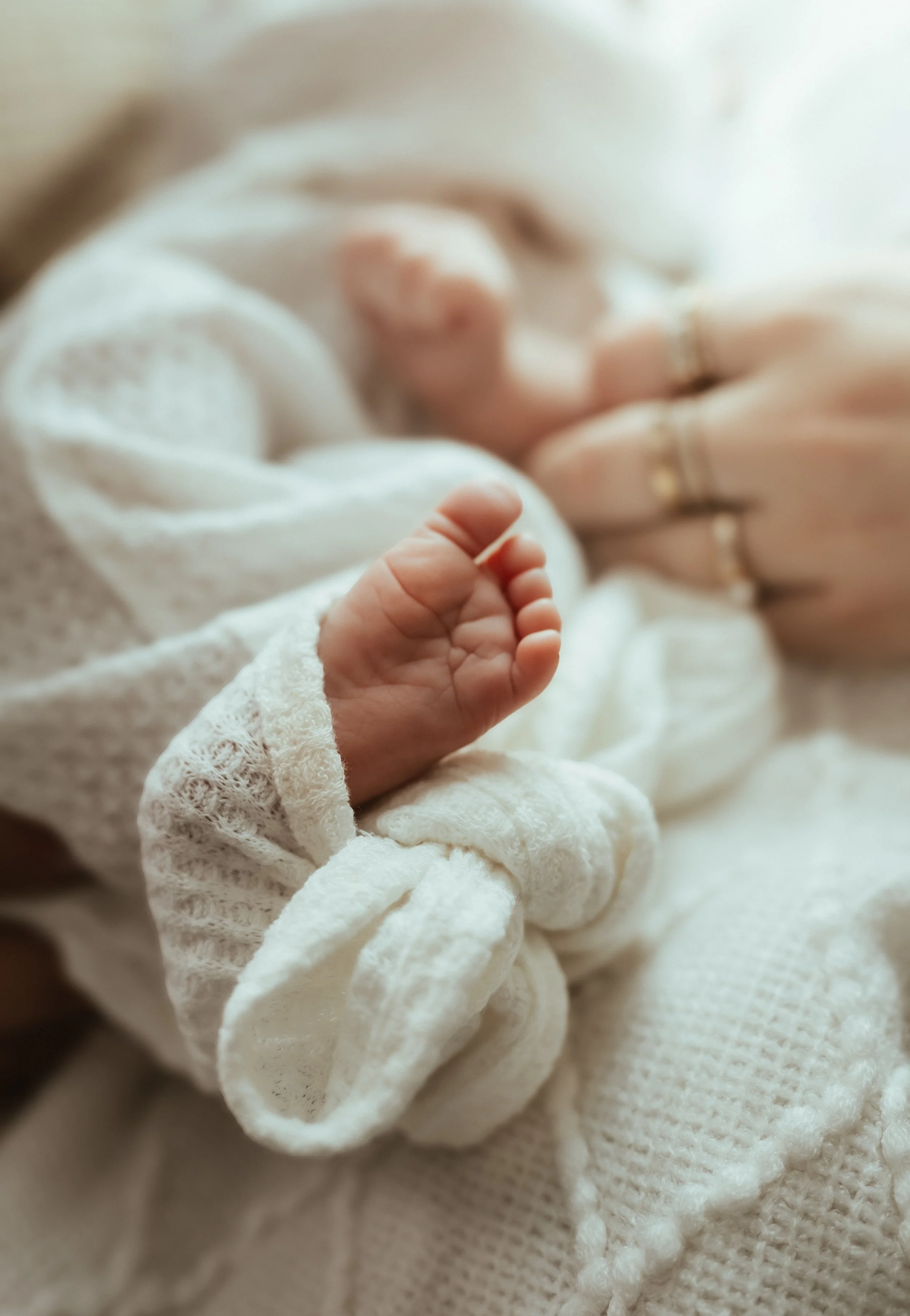 Close-up of a newborn baby's hand resting on a soft white blanket.