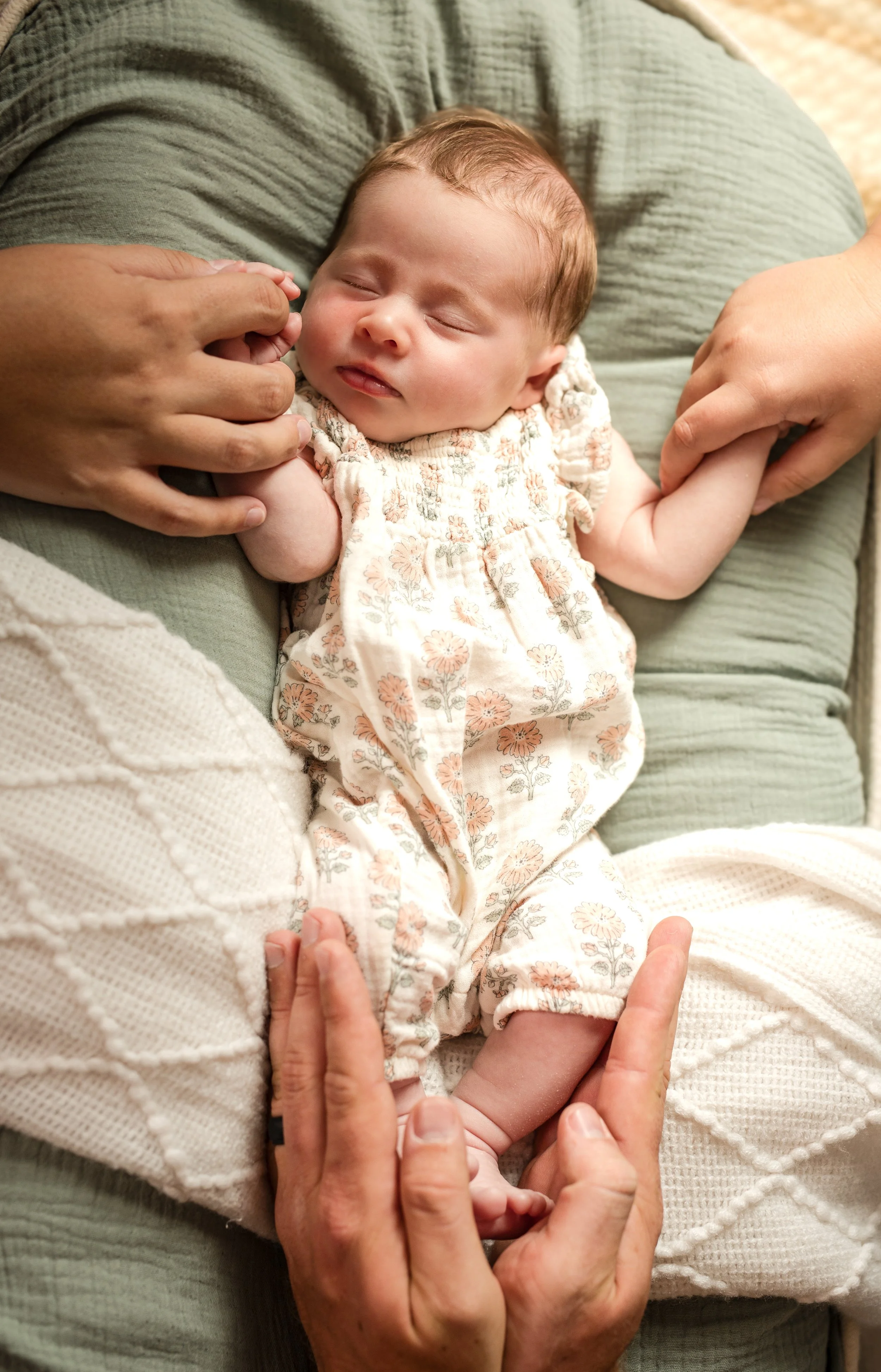 A person holding a sleeping baby with hands gently clasped together.