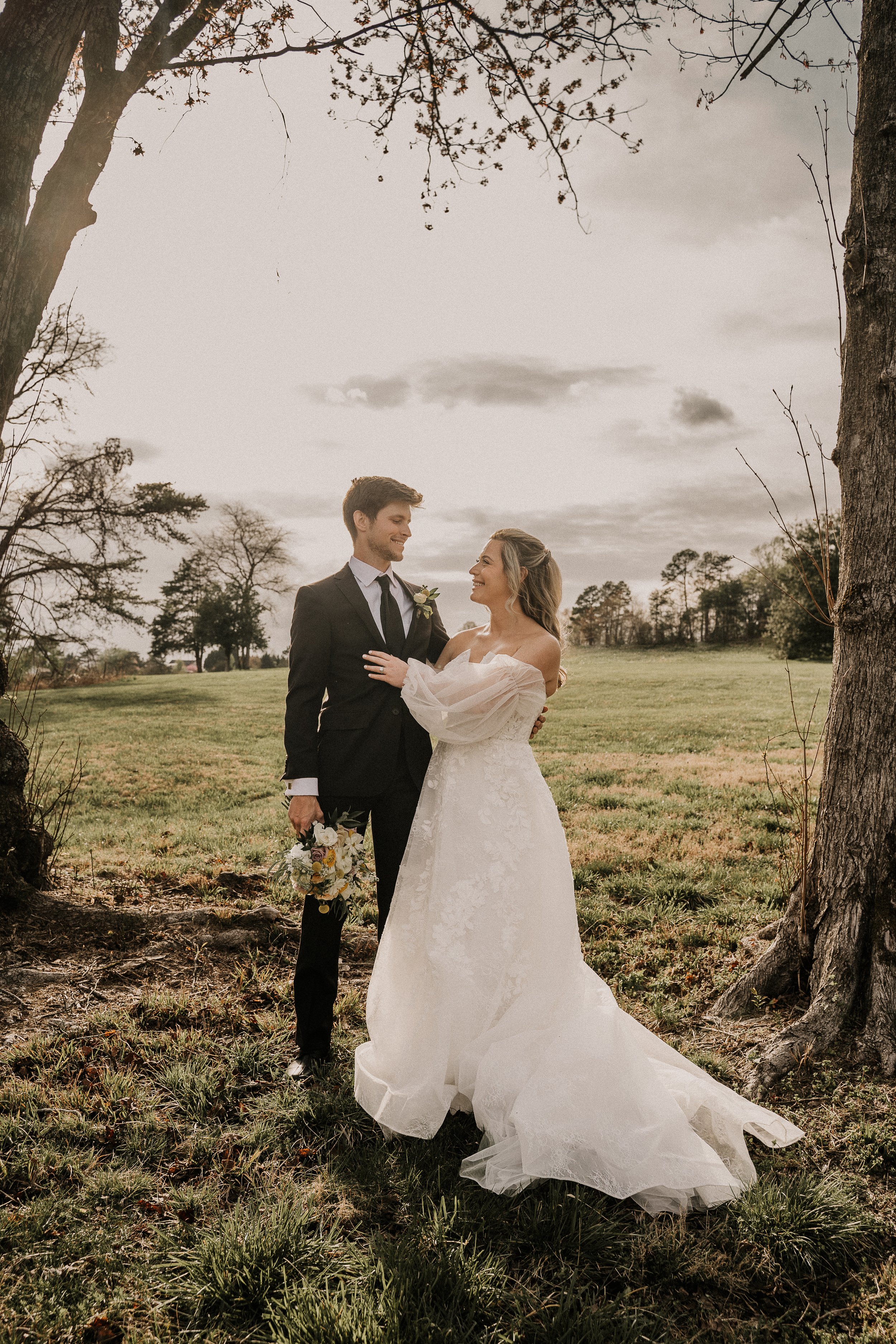 bride and groom holding each other in a meadow; how much does a wedding venue cost near Charlotte NC?
