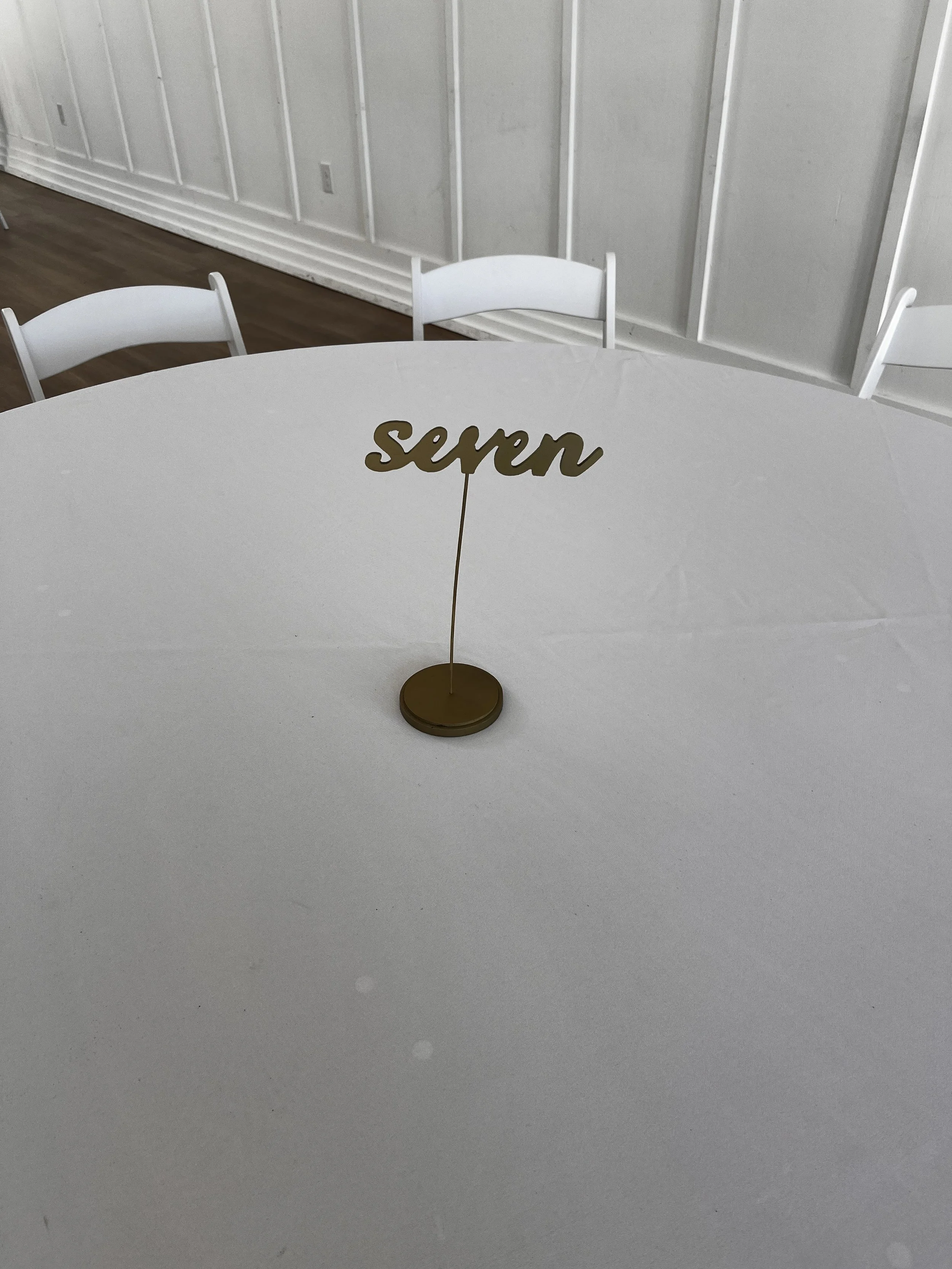 Gold table number words on stick at wedding venue