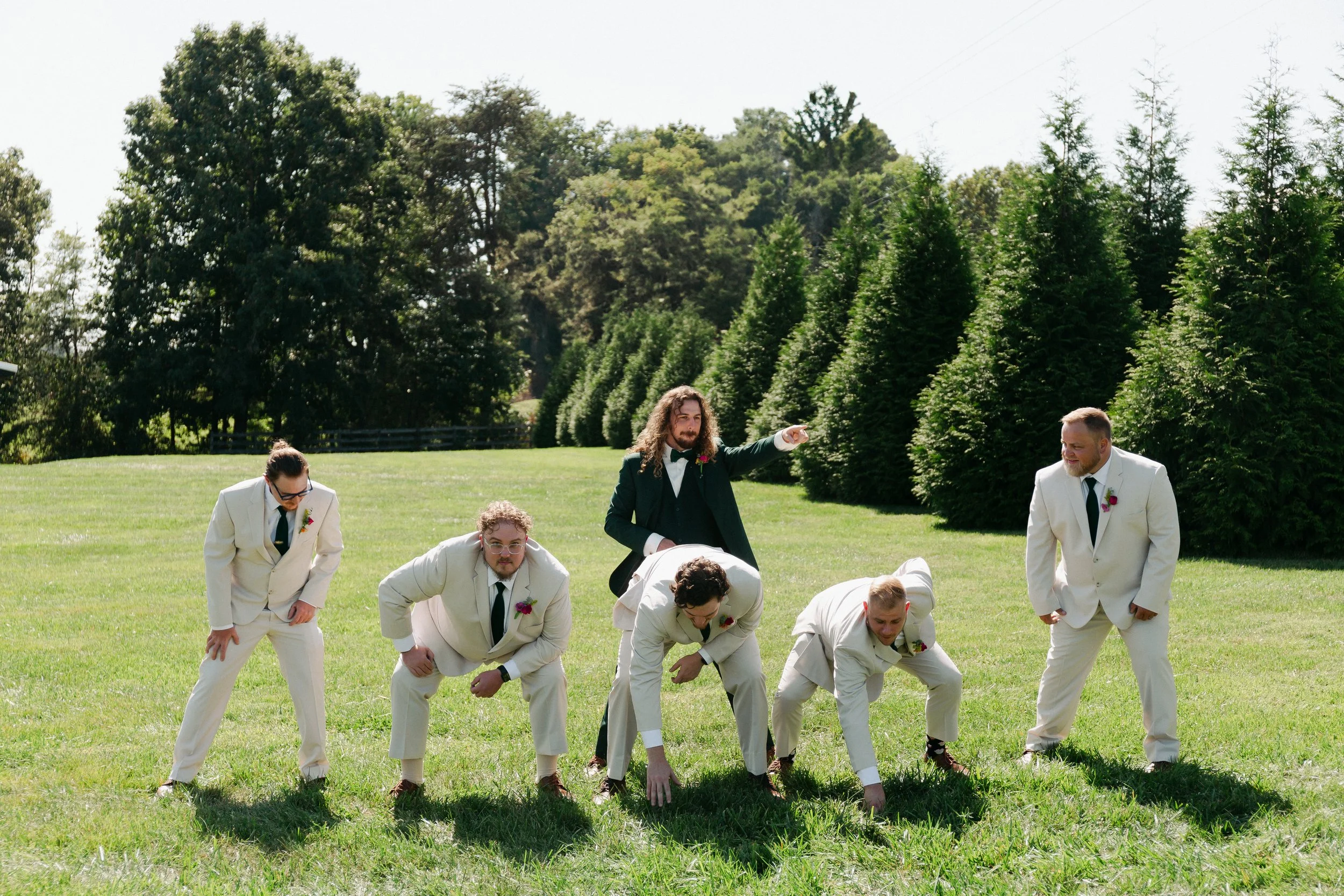 groom and groomsmen playing football in green field; outdoor wedding venues near Charlotte NC