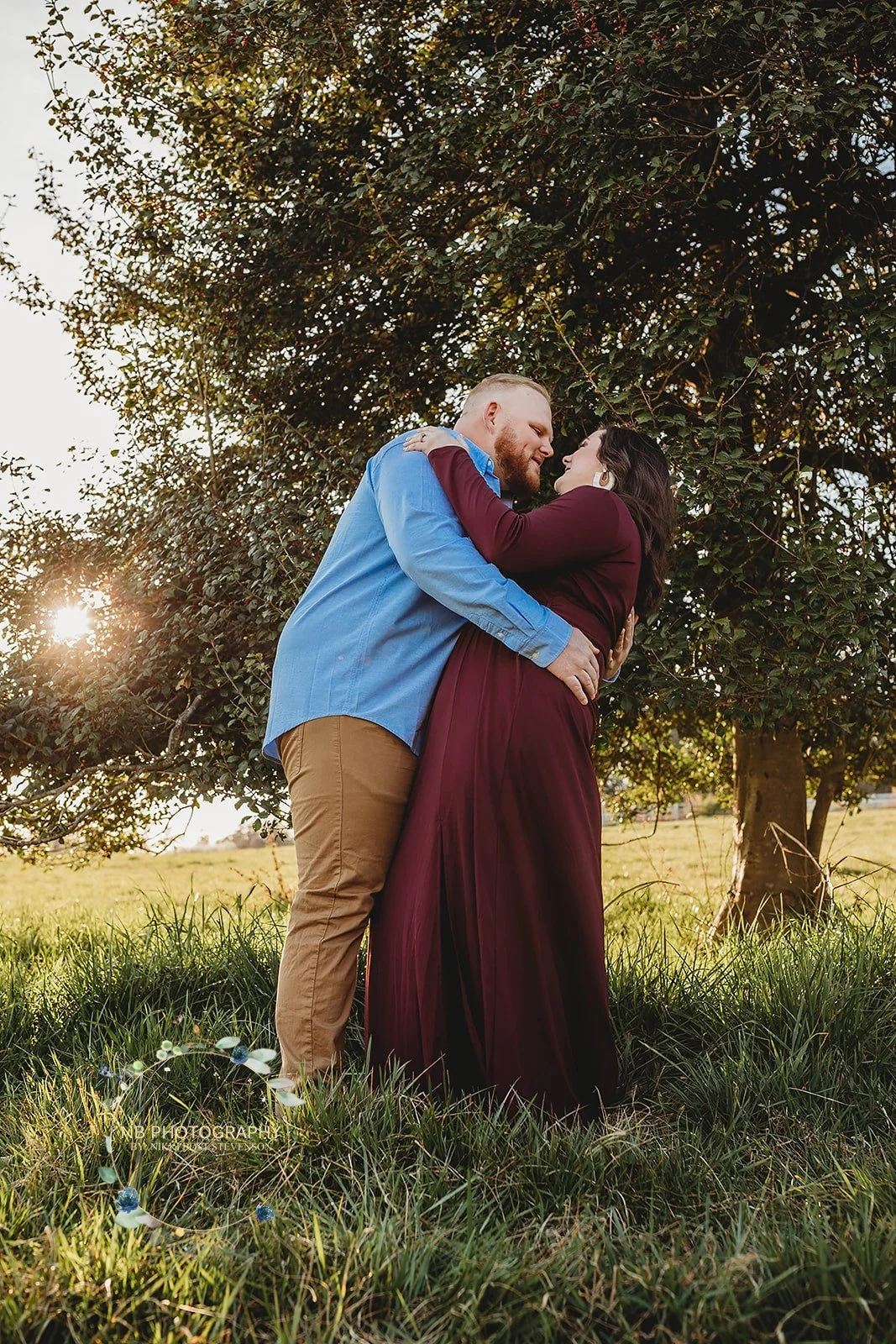 engaged couple hugging by tree; truth about free wedding websites