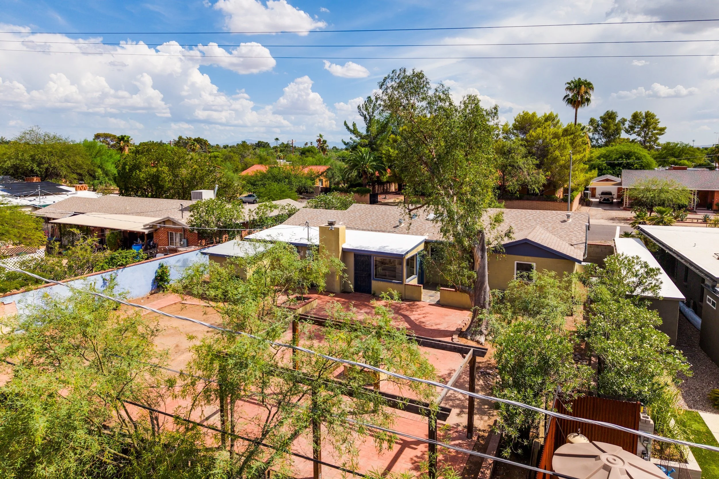 A suburban neighborhood with houses, trees, and a partly cloudy sky.