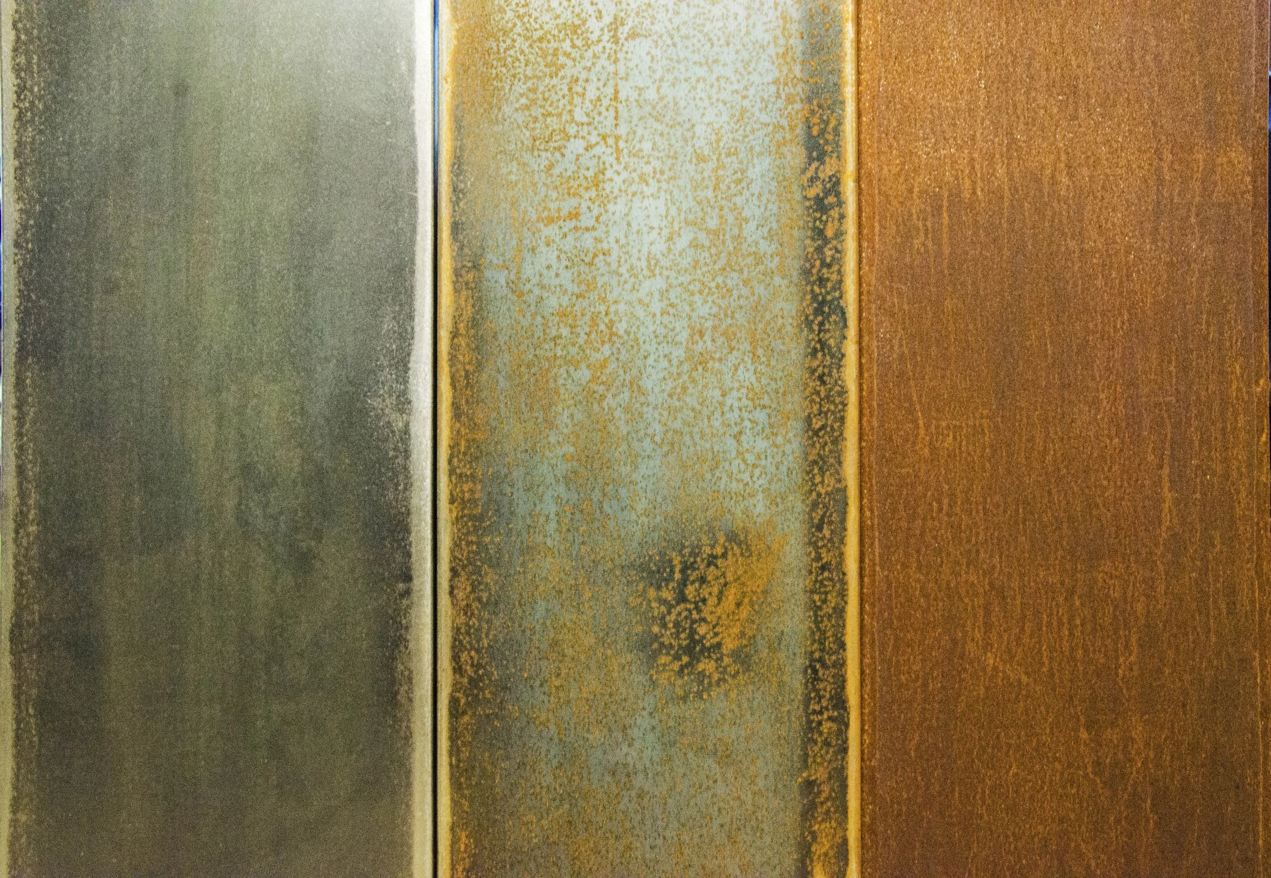Close-up of three rusted metallic surfaces in different colors: grey, light blue with rust spots, and brownish-orange.