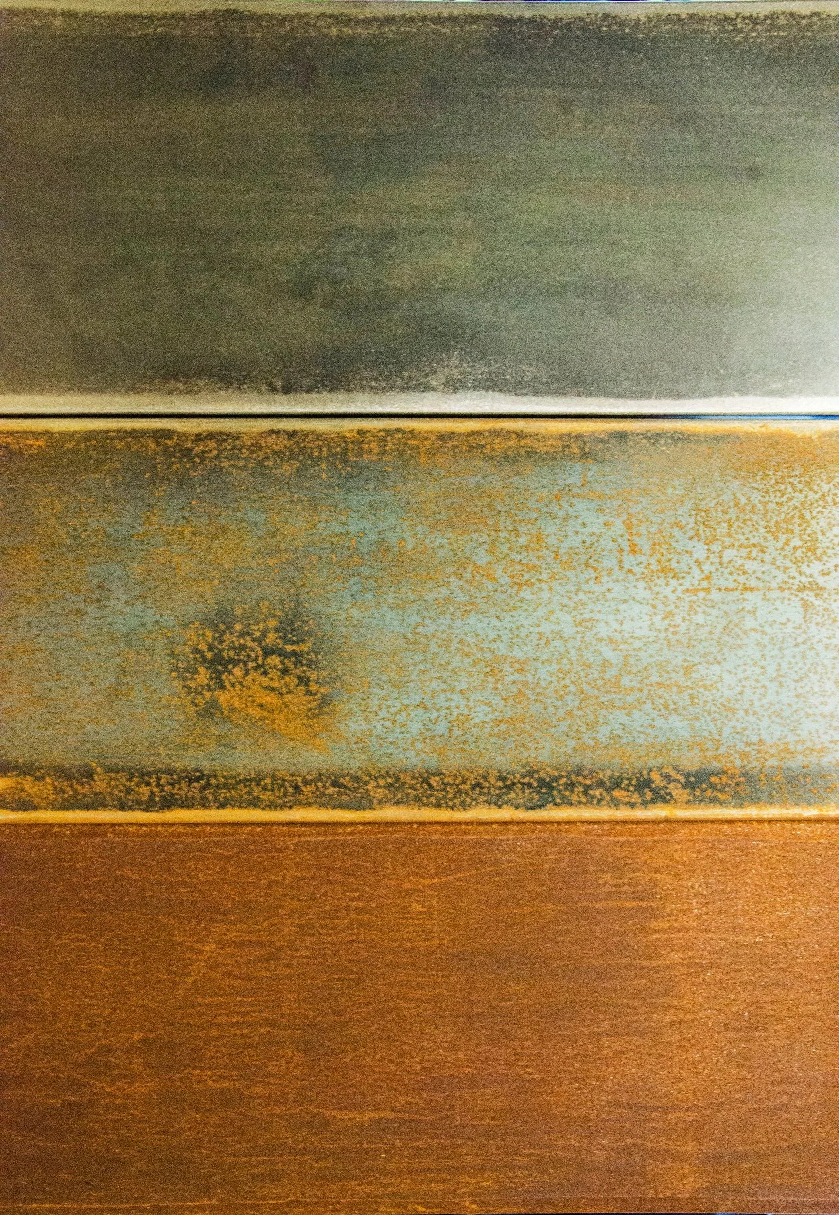 Close-up of three different colored and textured metal surfaces, showcasing rust and wear.