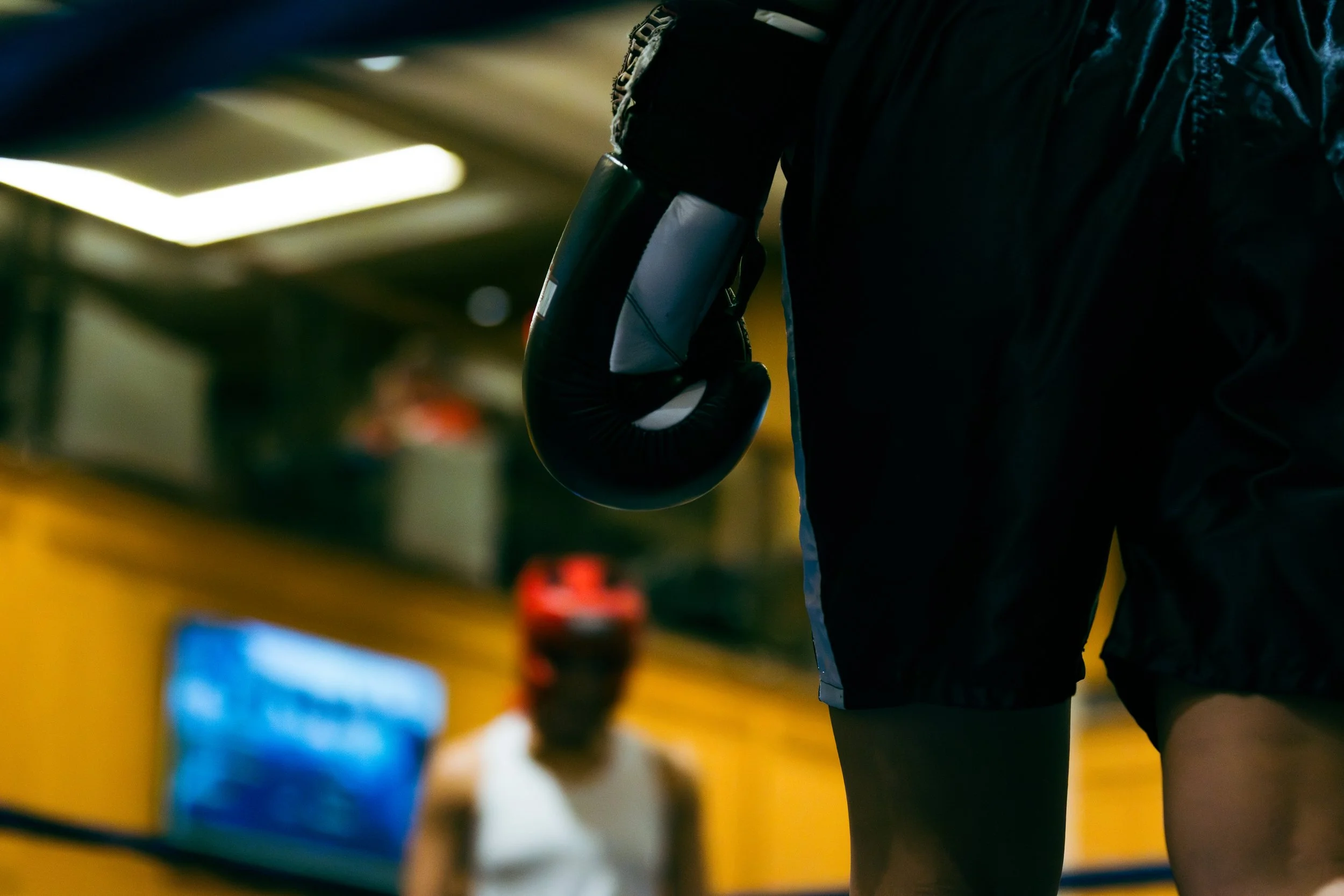A person wearing a black jacket and black gloves holding a motorcycle helmet in a dimly lit indoor parking garage.