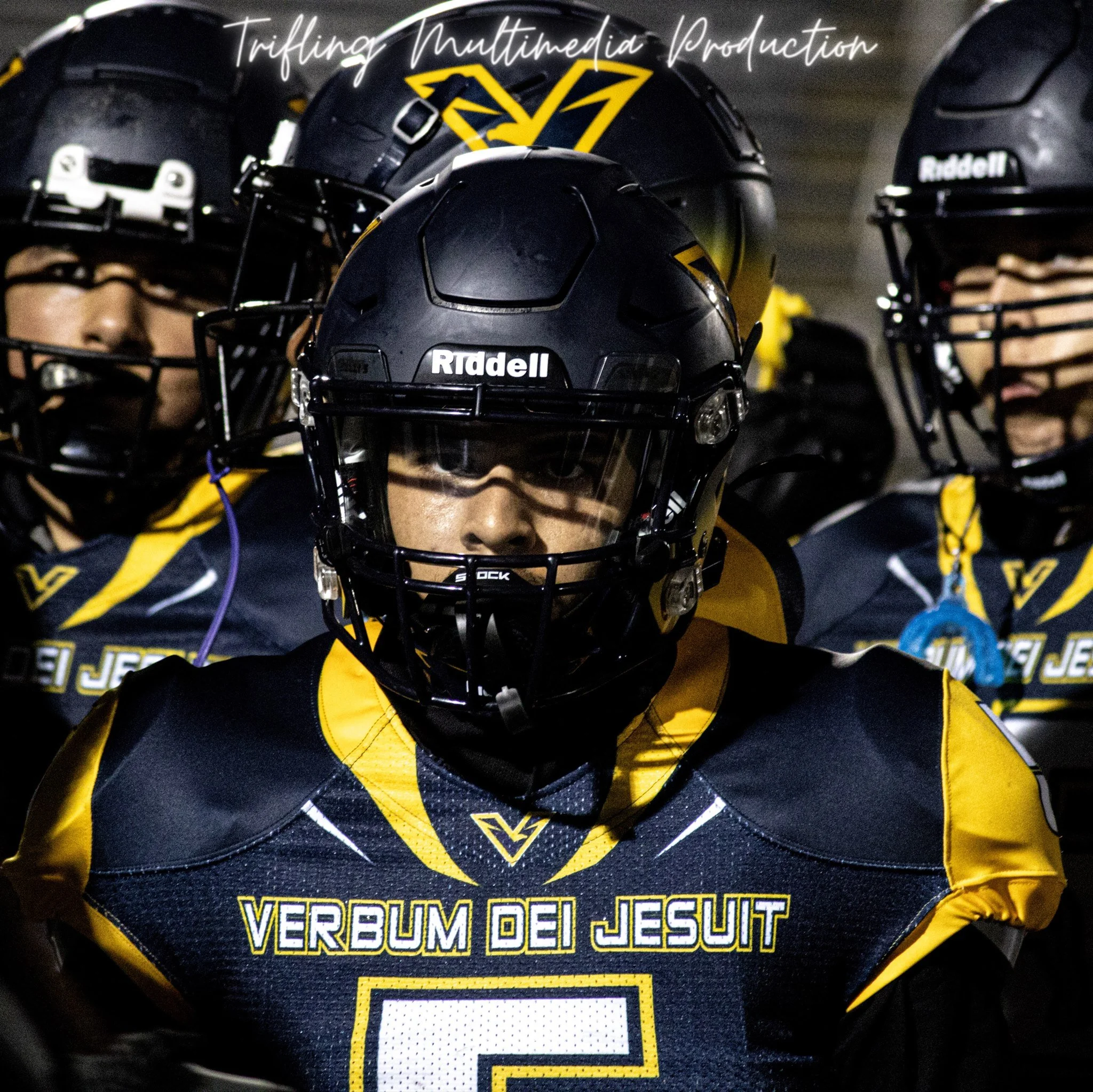 Close-up of a group of football helmets with Rams logos, worn by players in yellow and navy uniforms, during a nighttime game or practice.