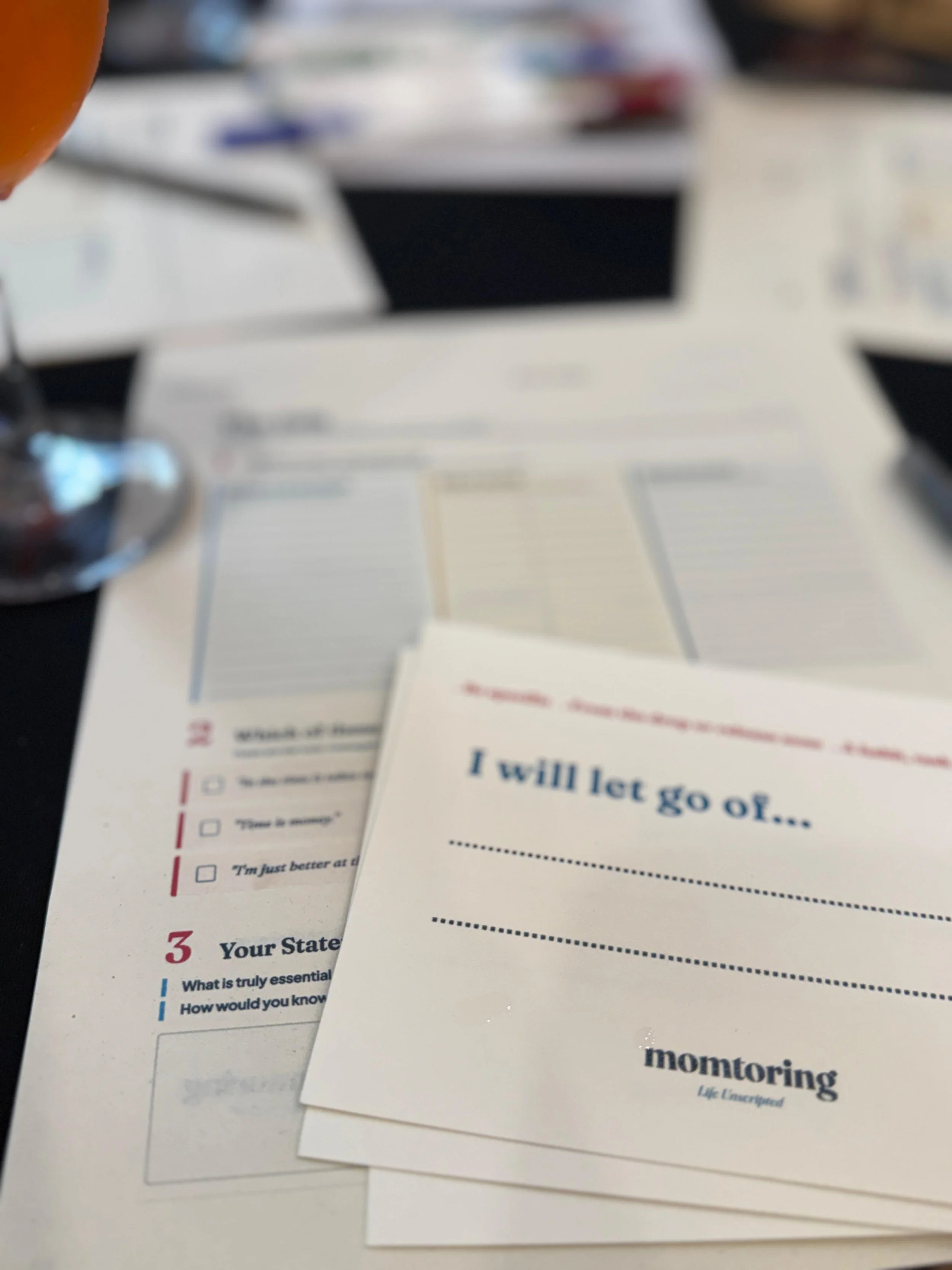 A focused, atmospheric view of printed workshop worksheets and pens laid out on a table for attendees.