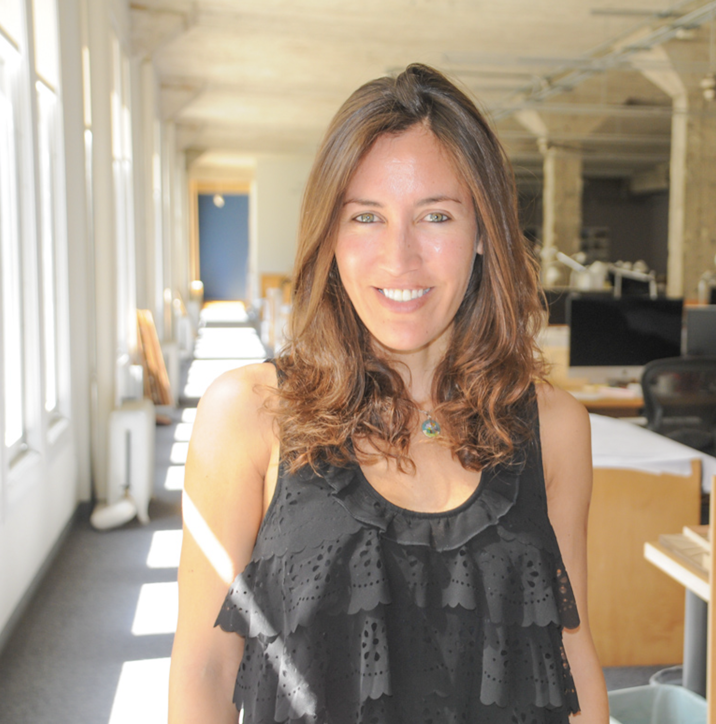 Andi Salcedo smiling in a sunlit corporate office hallway during her early marketing career before transitioning into professional motherhood coaching.