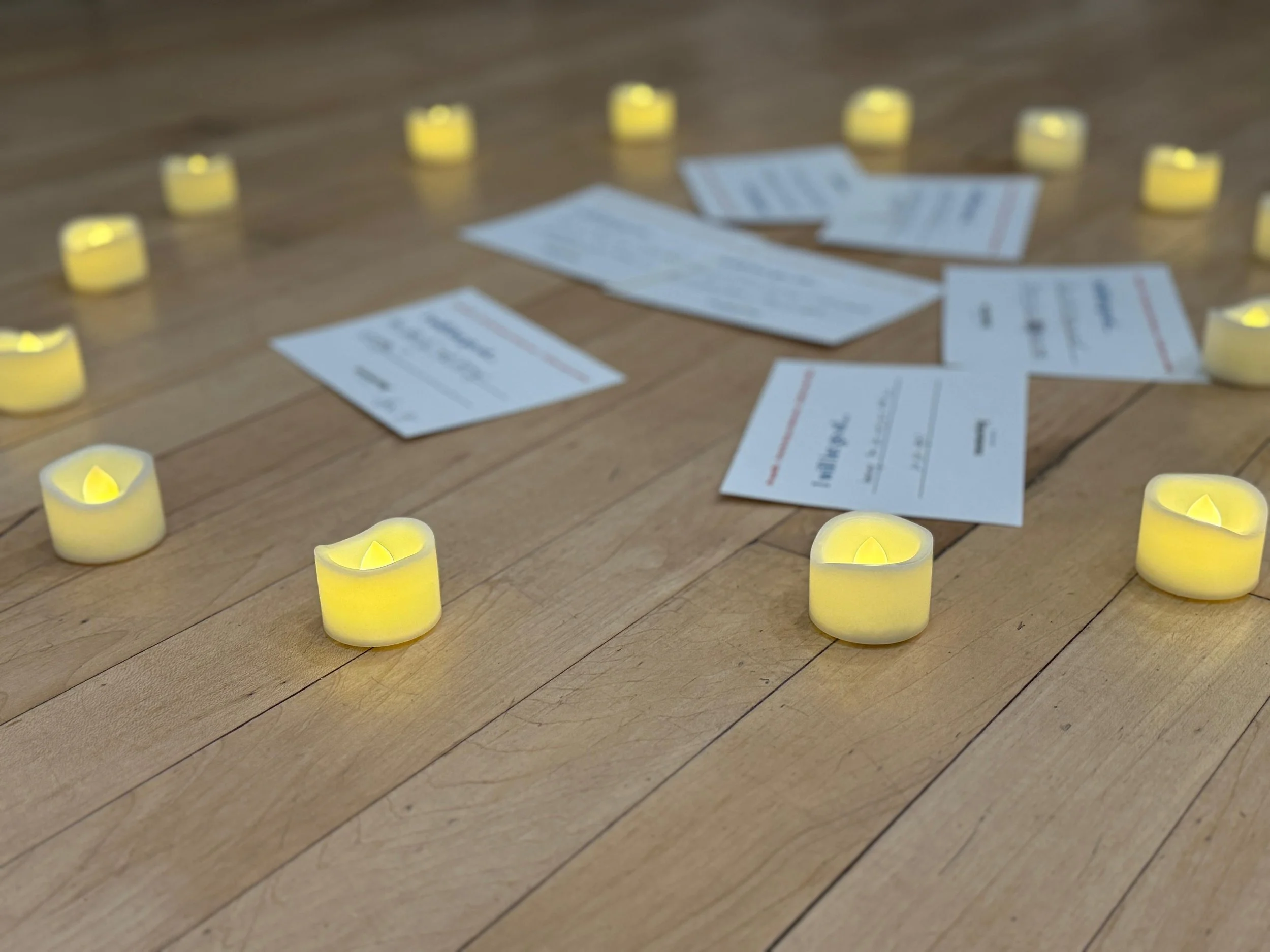 A close-up shot of handwritten commitment cards and tea light candles on a wooden table during a motherhood workshop.
