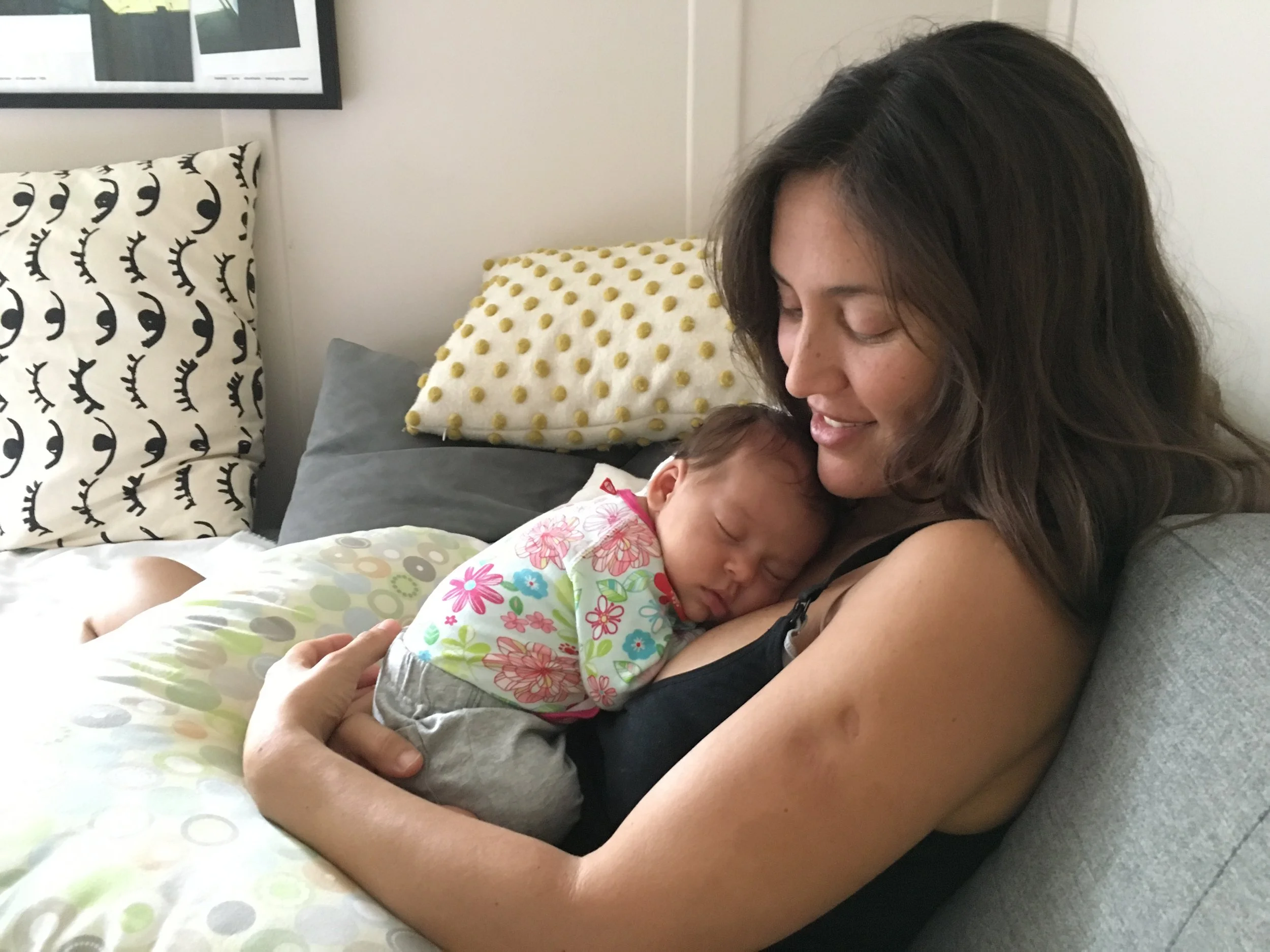 Andi Salcedo holding her newborn baby girl close to her chest at home, illustrating the emotional realities of returning to work after maternity leave.