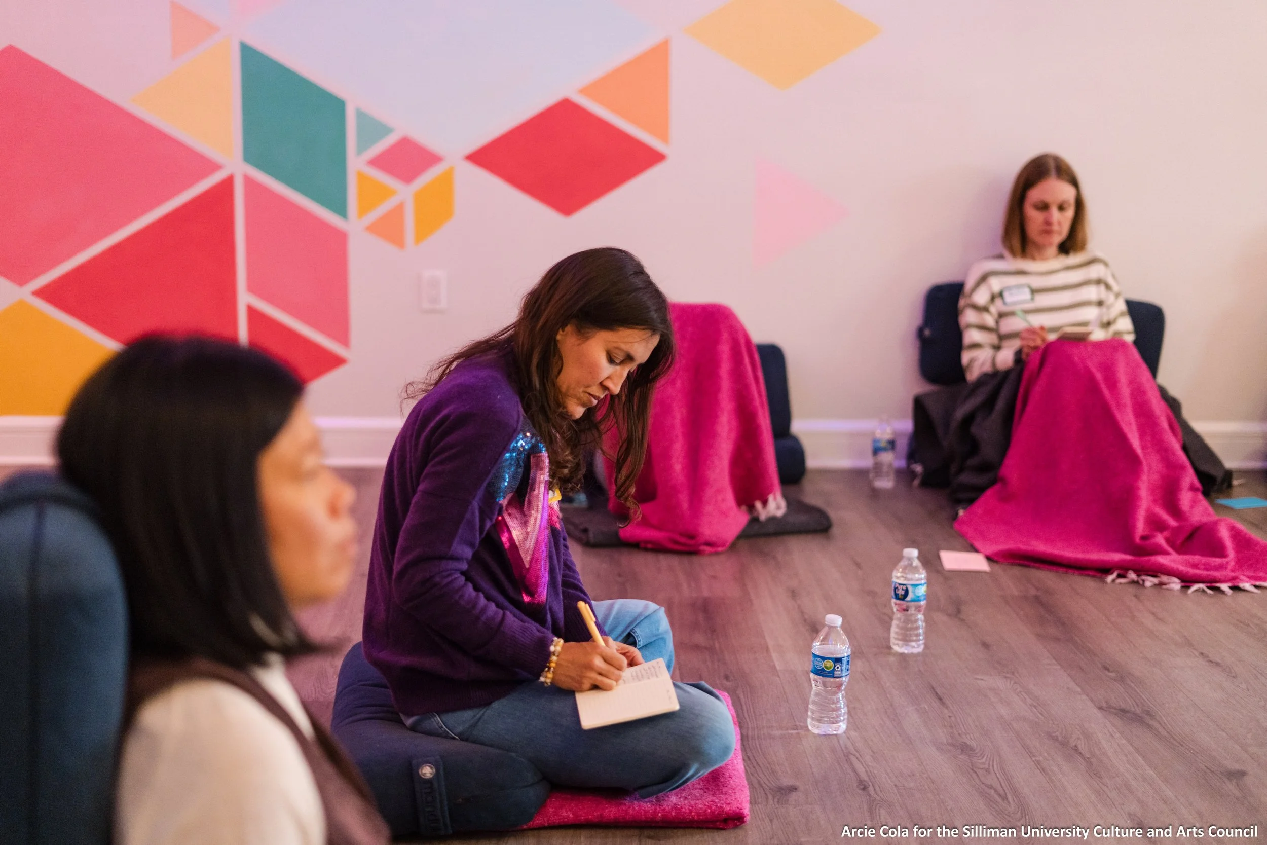 Women sitting on the floor in a supportive circle, writing down reflections in journals during an 8-week small group cohort journey.