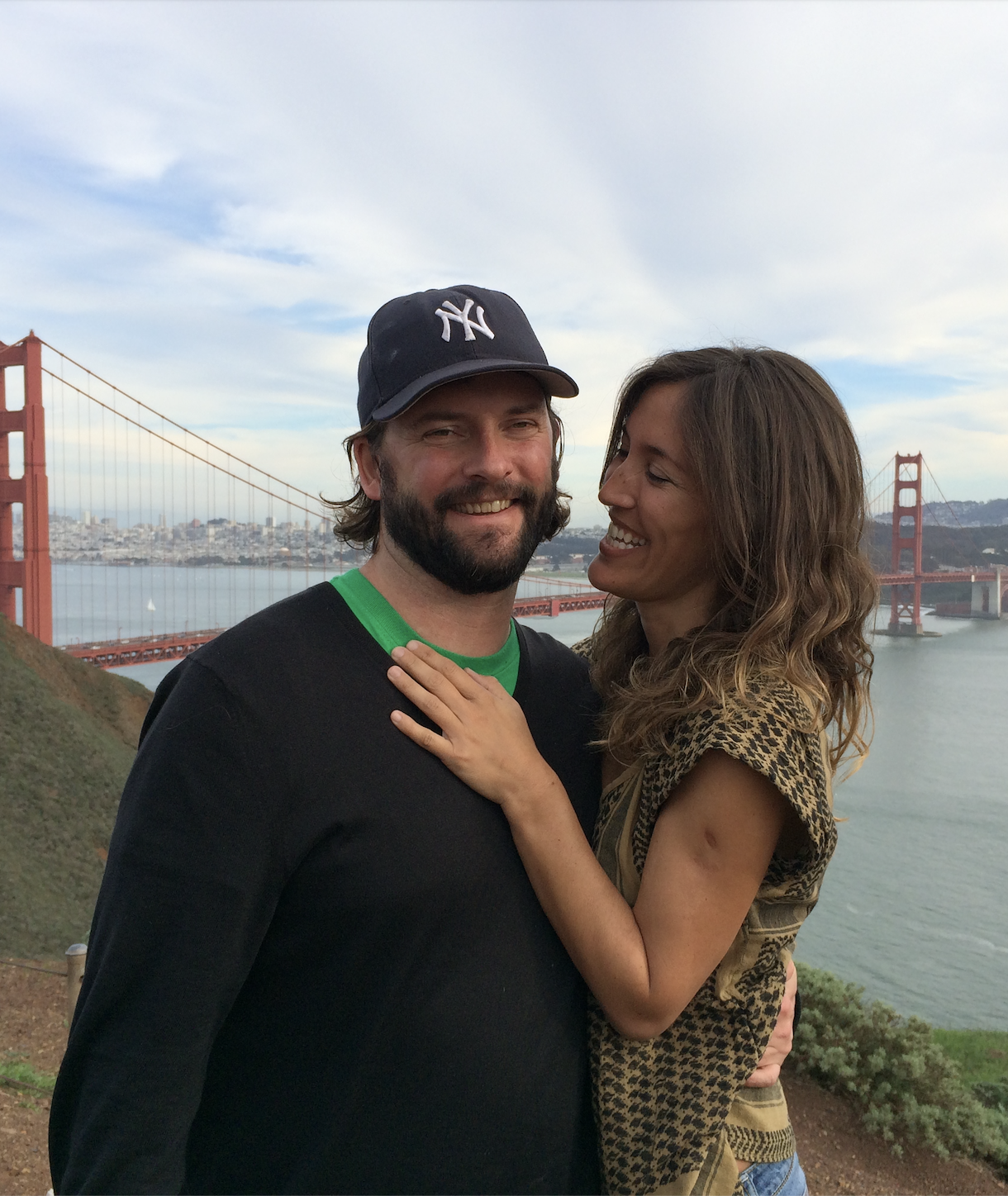 Andi Salcedo and her partner smiling together with the San Francisco Golden Gate Bridge in the background, representing a pivotal chapter of life travel and transition.