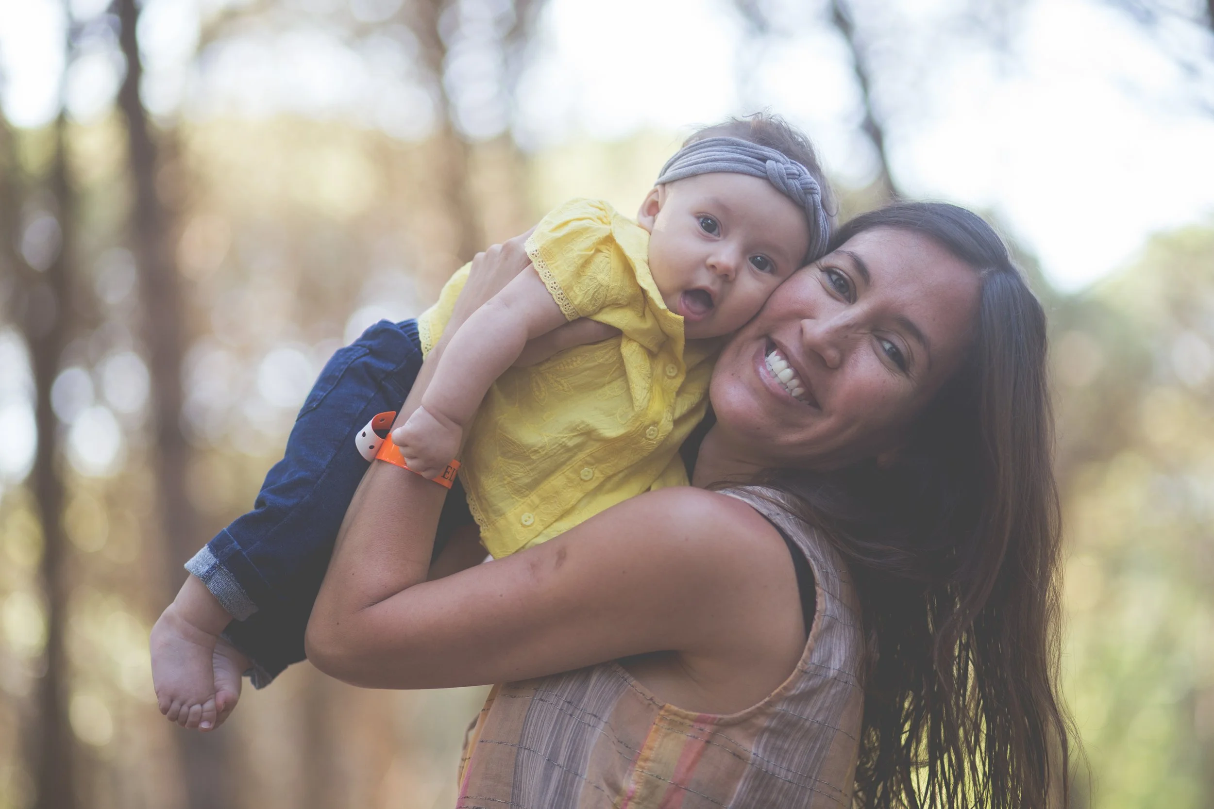 A close-up background photo of a mother smiling happily while holding her young child, inviting women to join the Return Ready coaching waitlist.