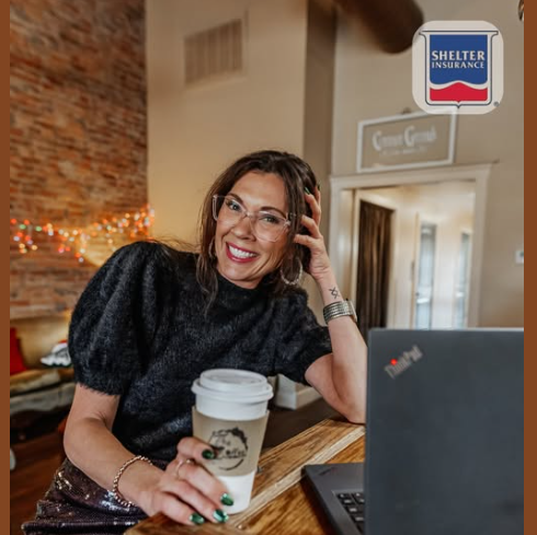 A woman holding a cup of coffee sitting in a coffee shop.