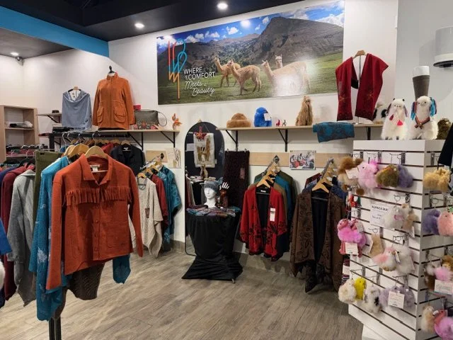 Display of clothing and accessories in a store, including jackets, sweaters, and stuffed animal keychains.