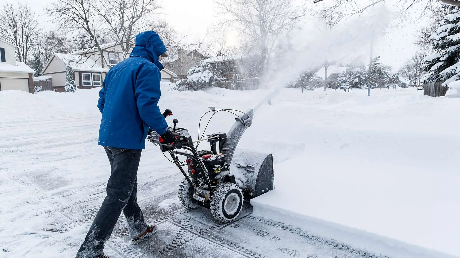Scoop Dog clearing a residential Ottawa driveway with a snow blower after a heavy snowfall