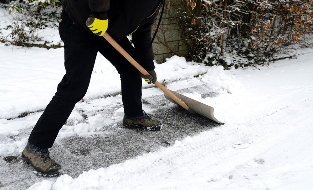 Person shovelling snow from a residential sidewalk and walkway in winter