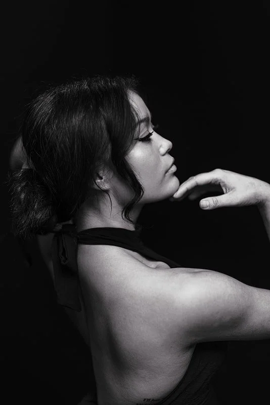 Black and white portrait of a woman posed elegantly against a dark background.