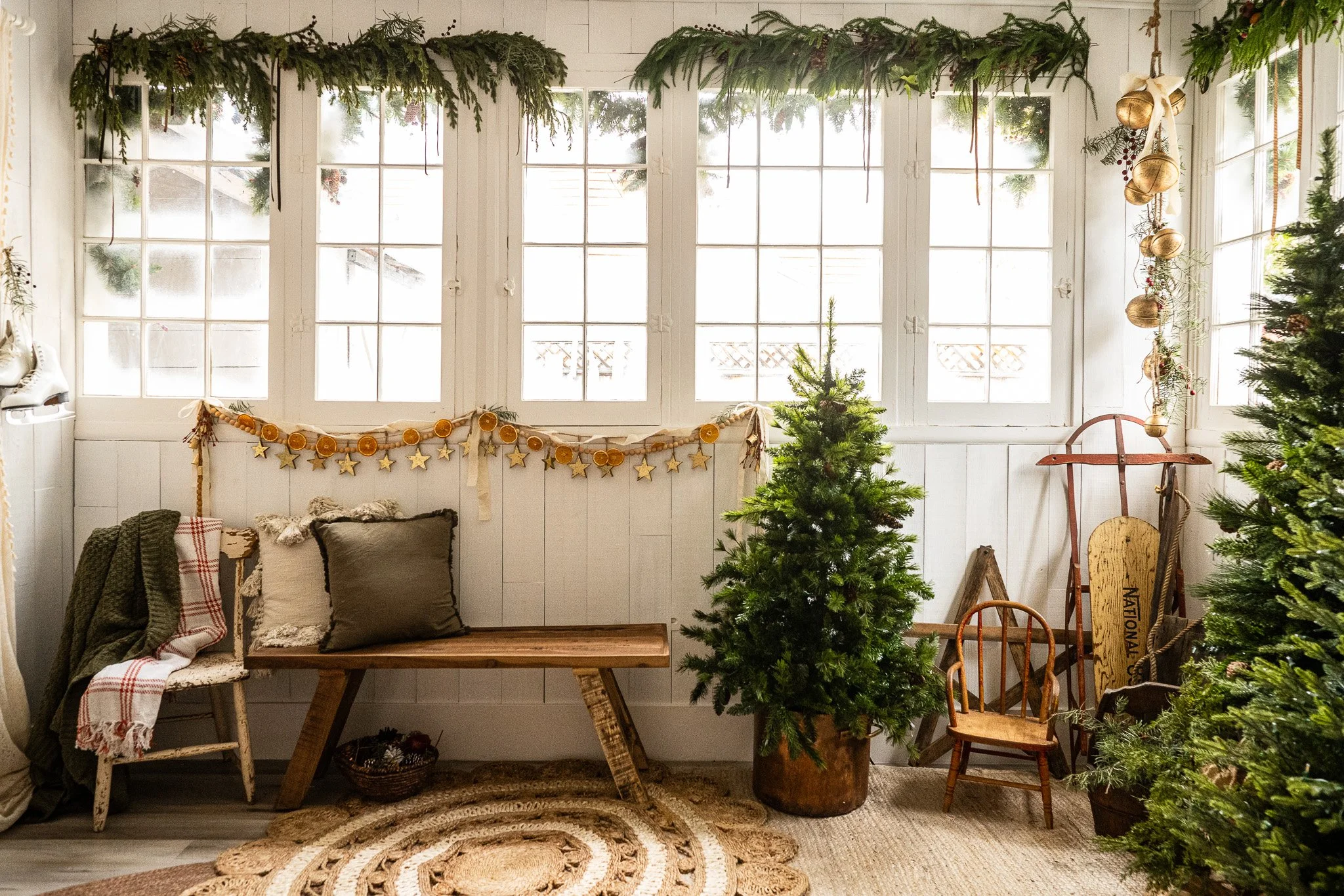 A cozy, festively decorated room with large windows, Christmas trees, and holiday ornaments.