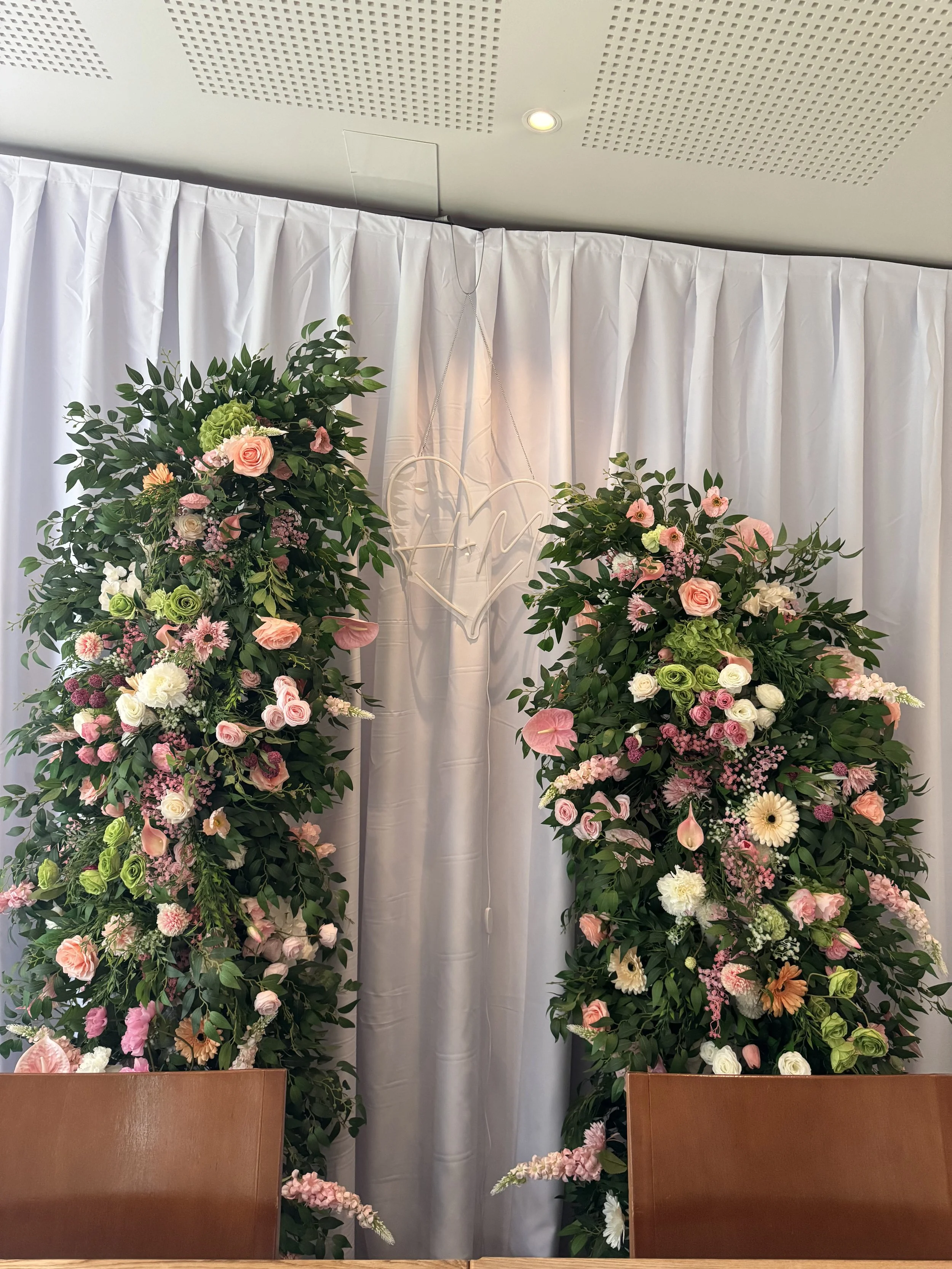 Håndlaget bryllupsbue dekorert med blomster under seremoni