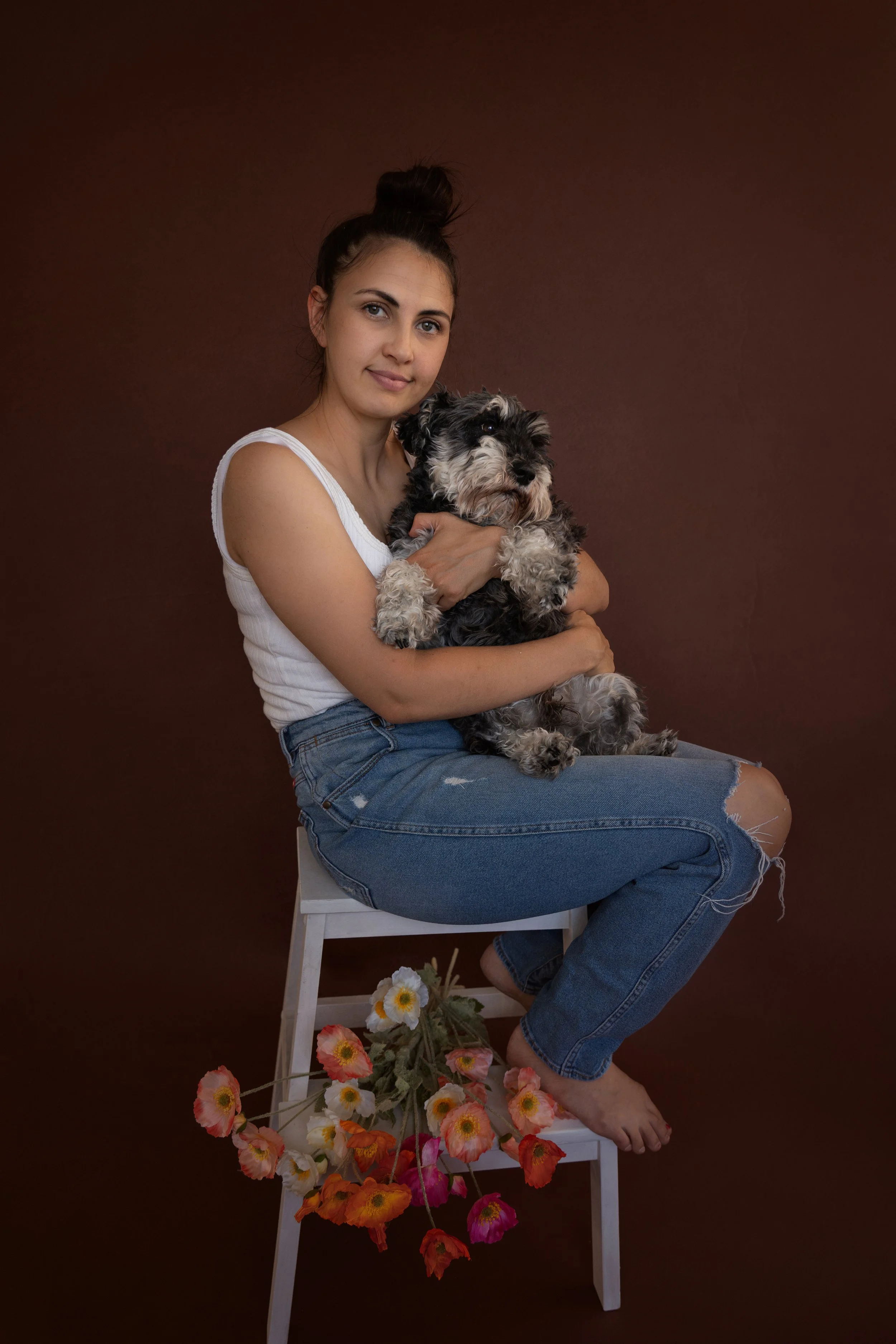 Chelsea Reidy from Chelsea Lou Photography holding her Mini Schanuzer dog in a studio photograph